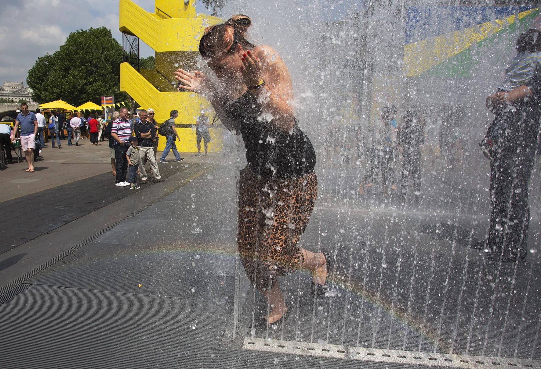 Woman egged on by her friend, takes the plunge to exit the Appearing Rooms fountains.