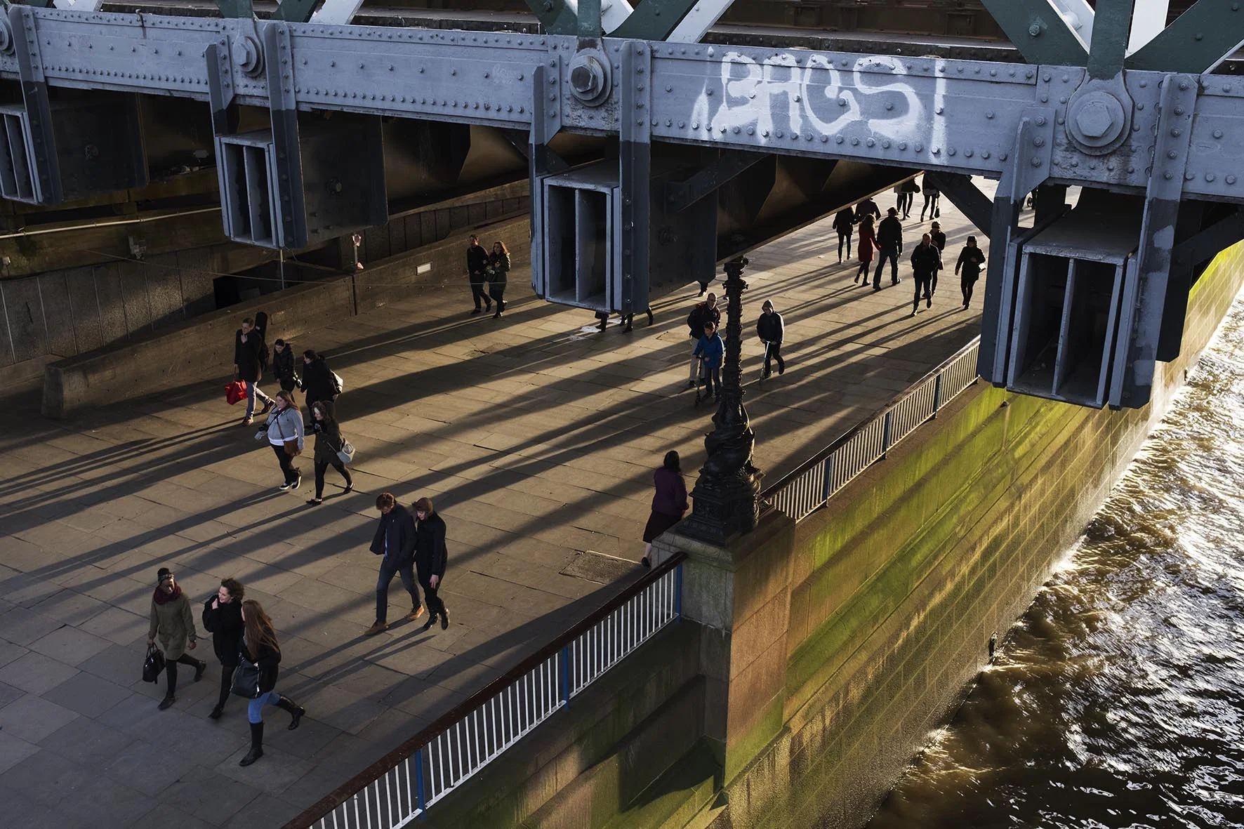 Winter light long shadows on the riverside walkway at Hungerford Bridge.