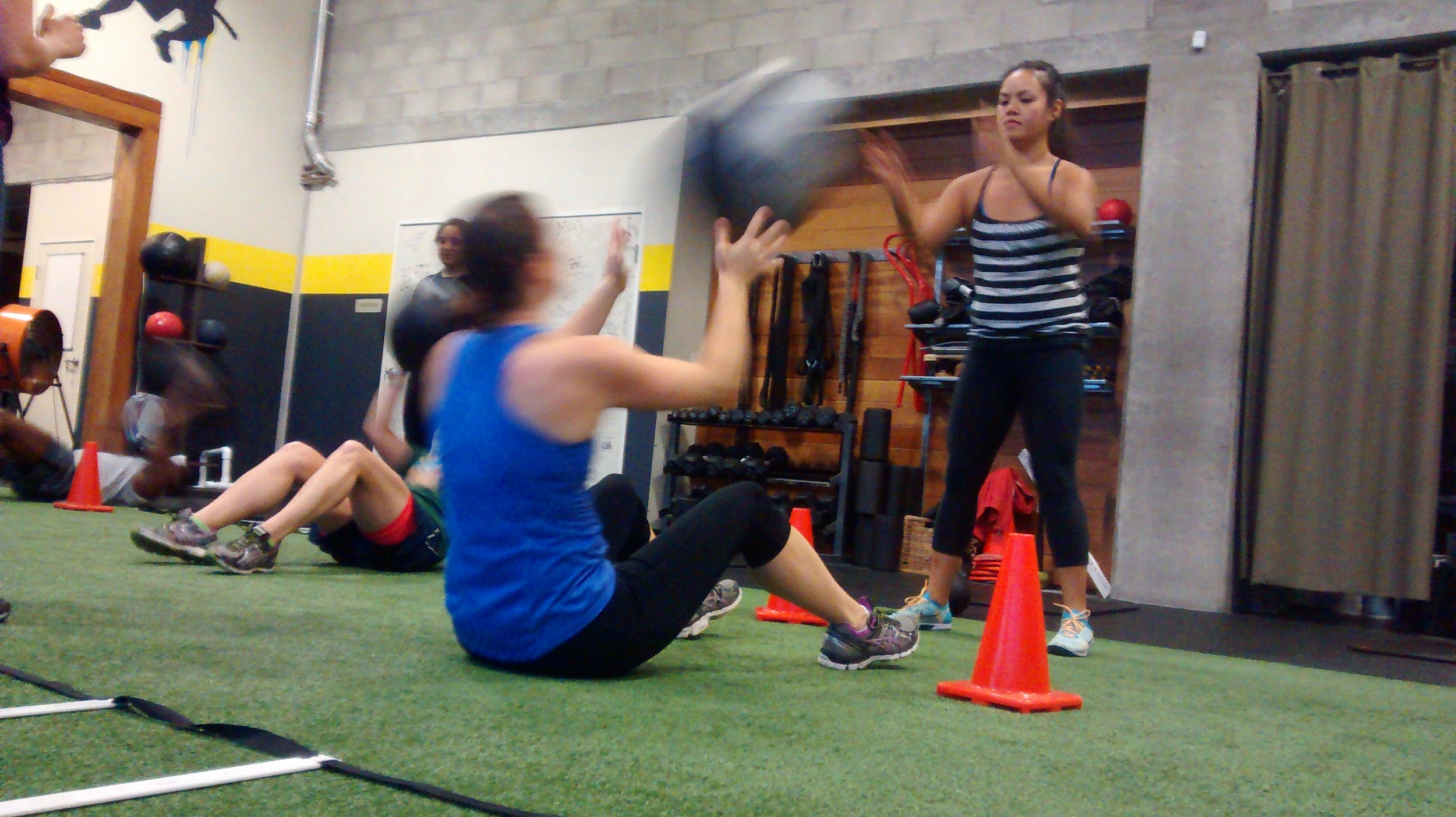 Dina is challenging her core activation and balance while also engaging her hand-eye coordination