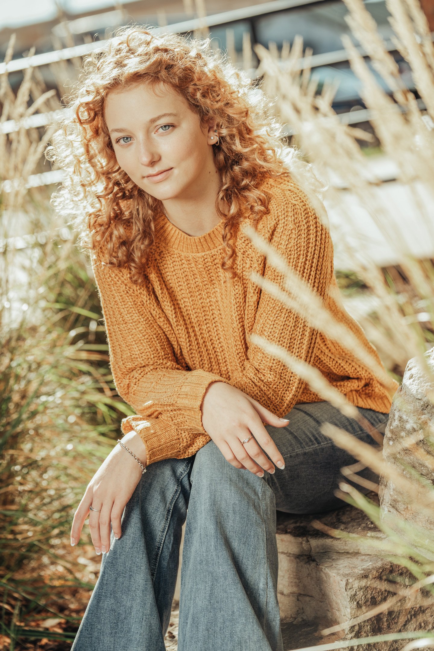 Mustard yellow sweater outfit on girl sitting on rock surrounded by wheat