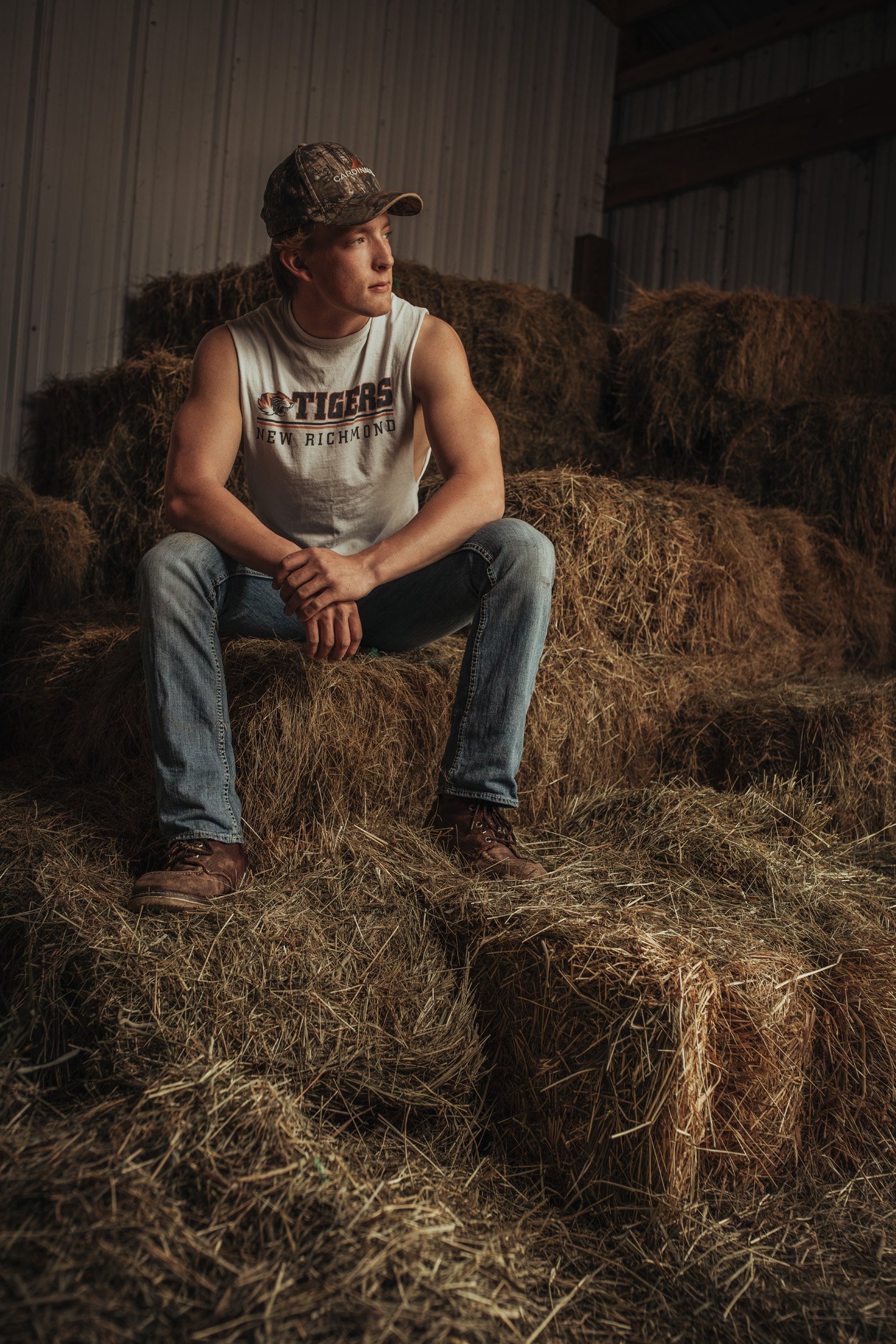 Barn full of hay bales with senior boy sitting on top