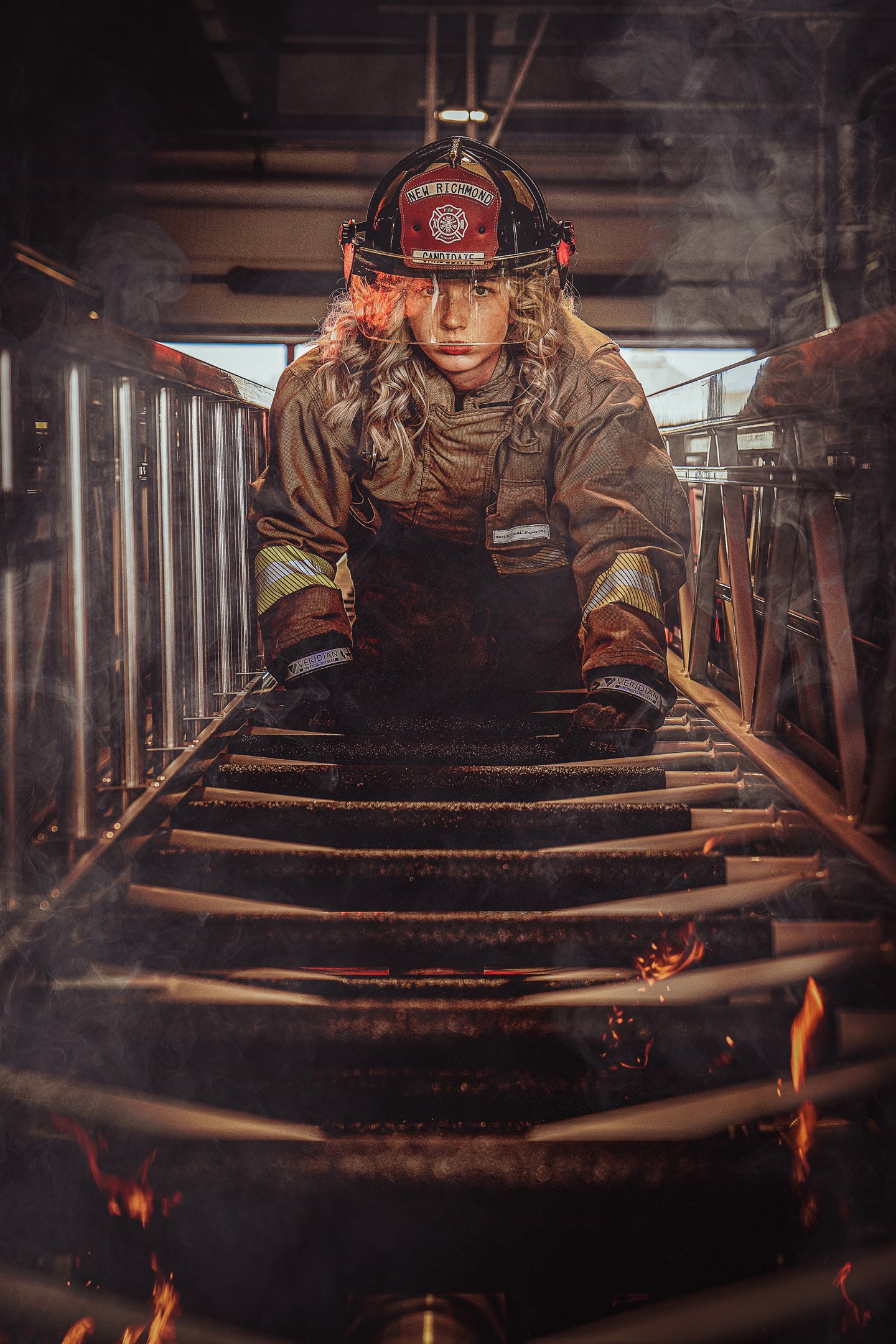 Firefighter female climbing up ladder on fire truck in full gear