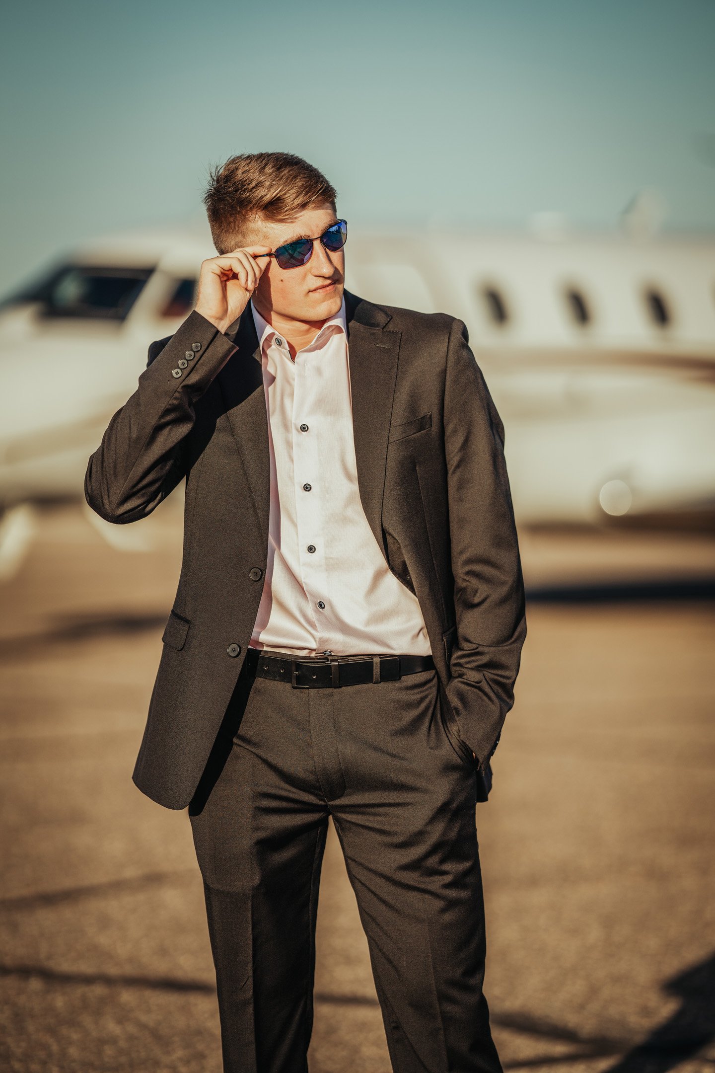Close up of senior boy in suit looking off into distance through sunglasses