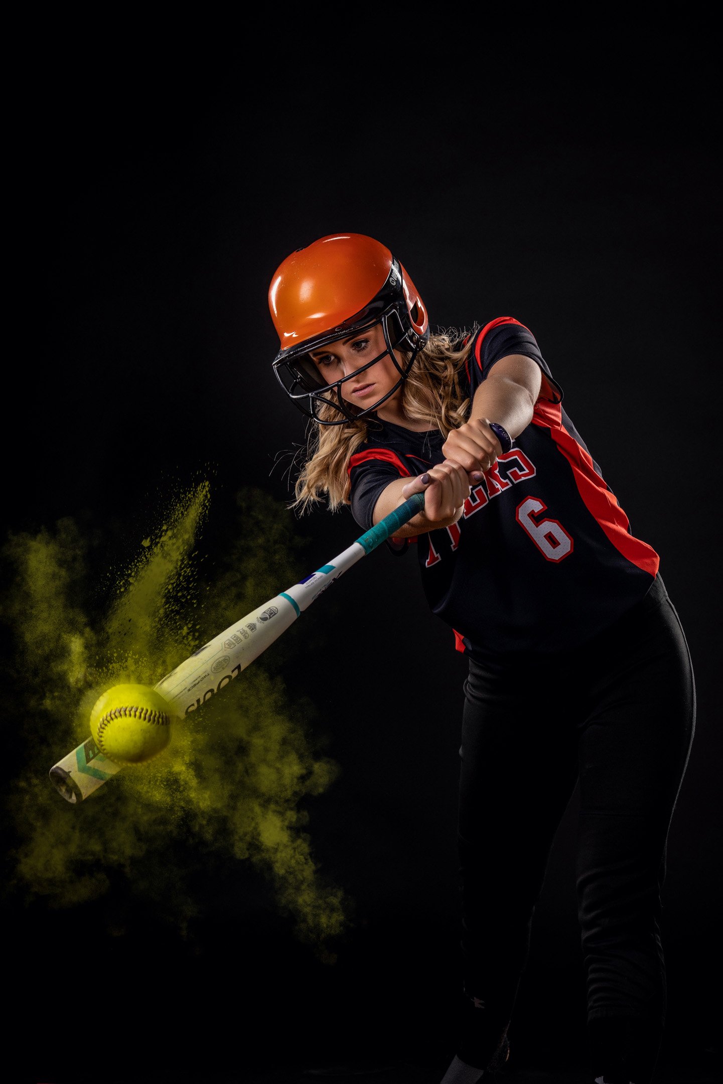 Softball player hitting the softball with bat and color splattered