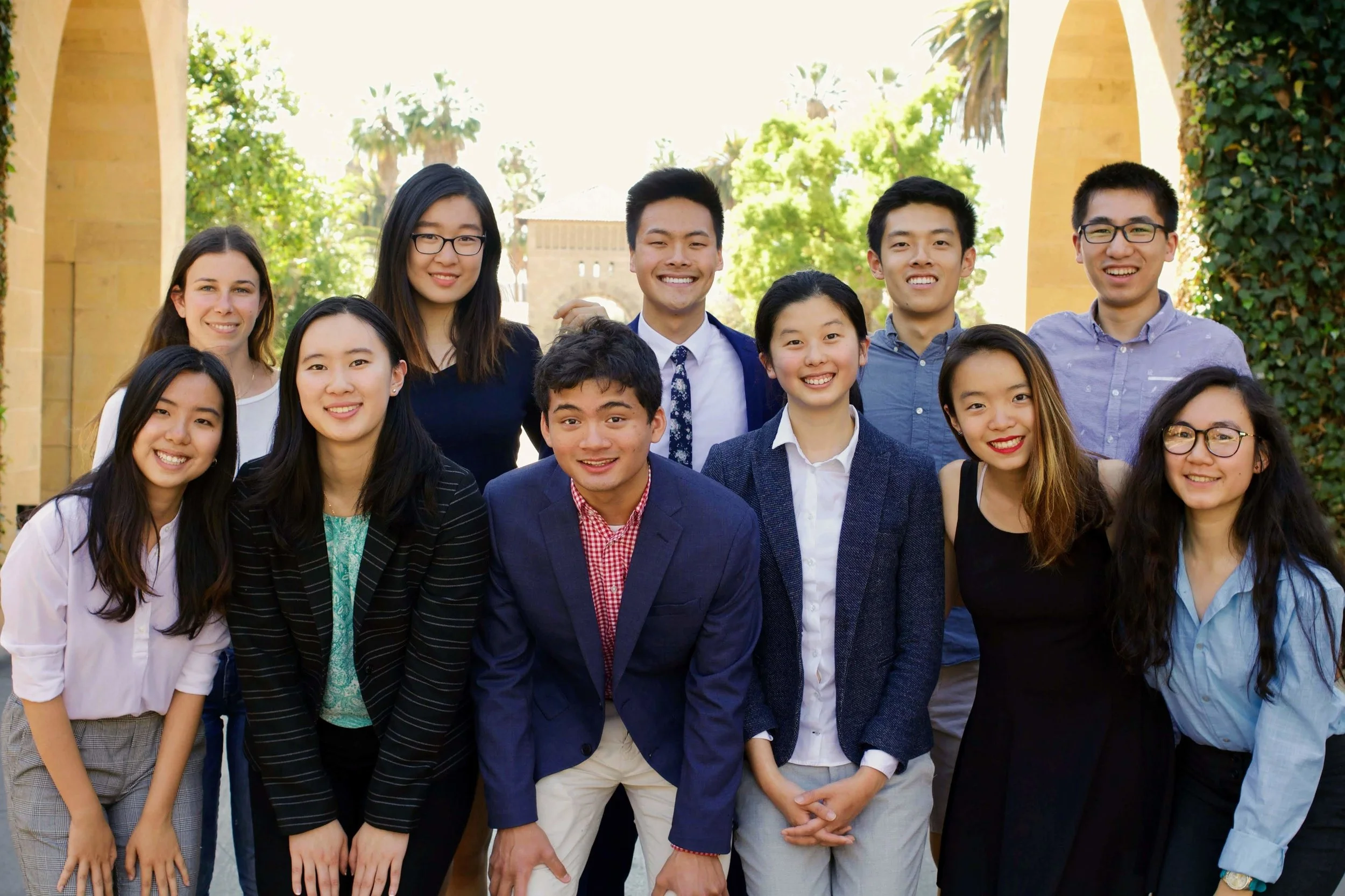 The 2018-19 Stanford FACES Executive Team poses for a collegial photo on Stanford's historic main quad. Pictured from left to right, front row: Zhenqi Hu (Vice President, On-Campus Programming), Caroline Zhang (Vice President, Alumni Relations), Nikhil Shankar (Co-President), Celia Xinuo Chen (Co-President), Victoria Yaqing Yang (Executive Member), Cathy Dao (Vice President, Budget). Back row: Cami Katz (Vice President, Telesummit), Lilian Kong (Outgoing Co-President), Troy Shen (Executive Member), Zecheng Wang (Vice President, Chapter Relations), Yulou Zhou (Executive Member). Not pictured: Andrew Tang (Executive Member), Francesca Lupia (Outgoing Co-President and Executive Member).