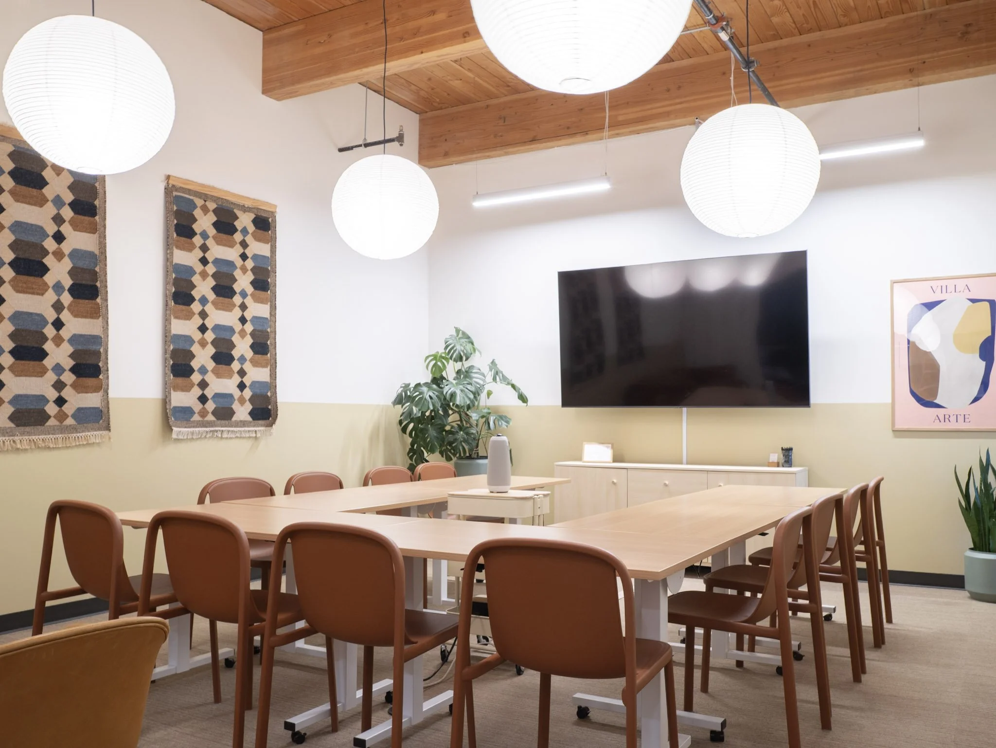 A u shaped conference room with paper lantern pendant lights and a large TV
