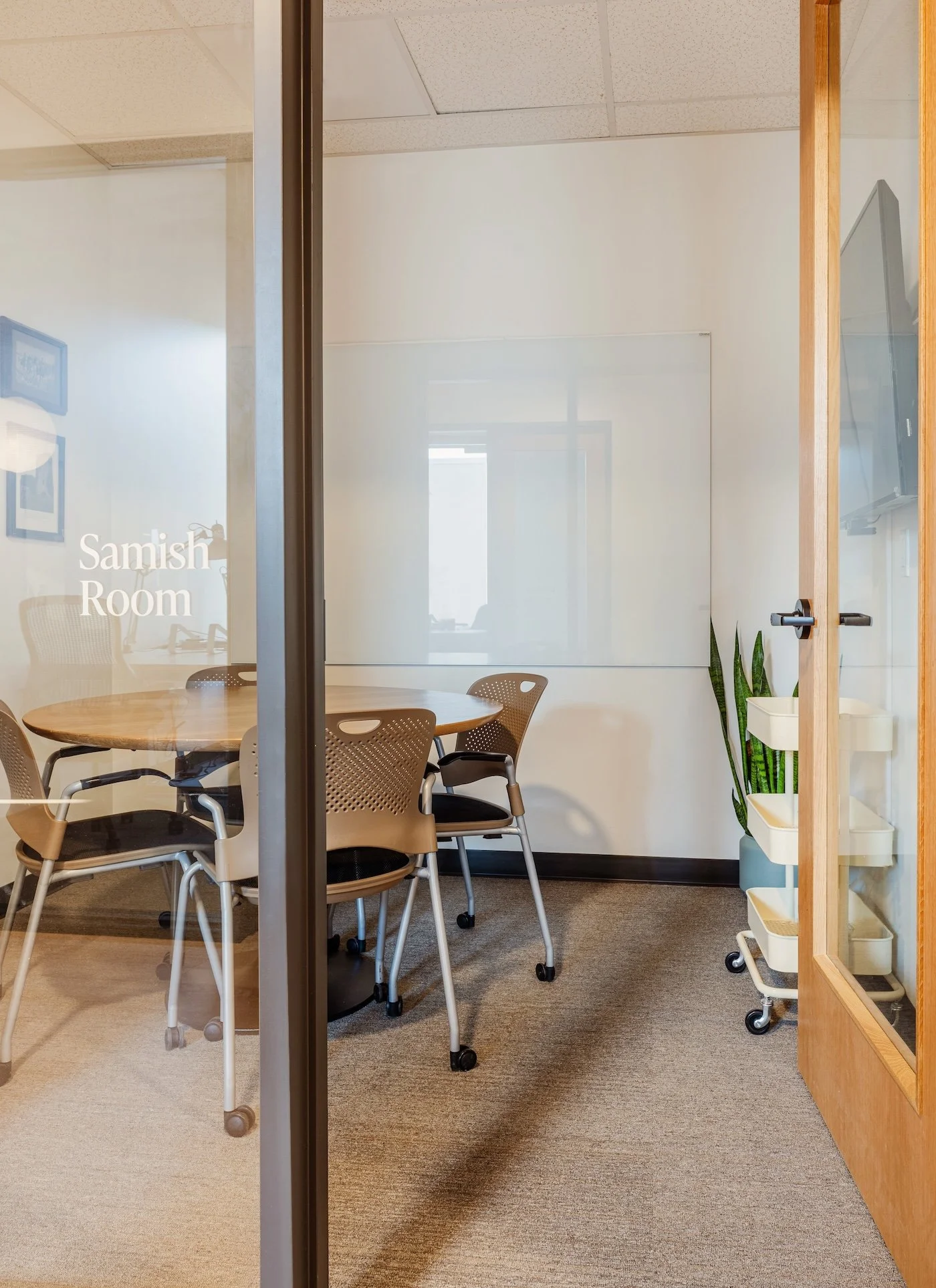 A small huddle room with a large whiteboard and round table