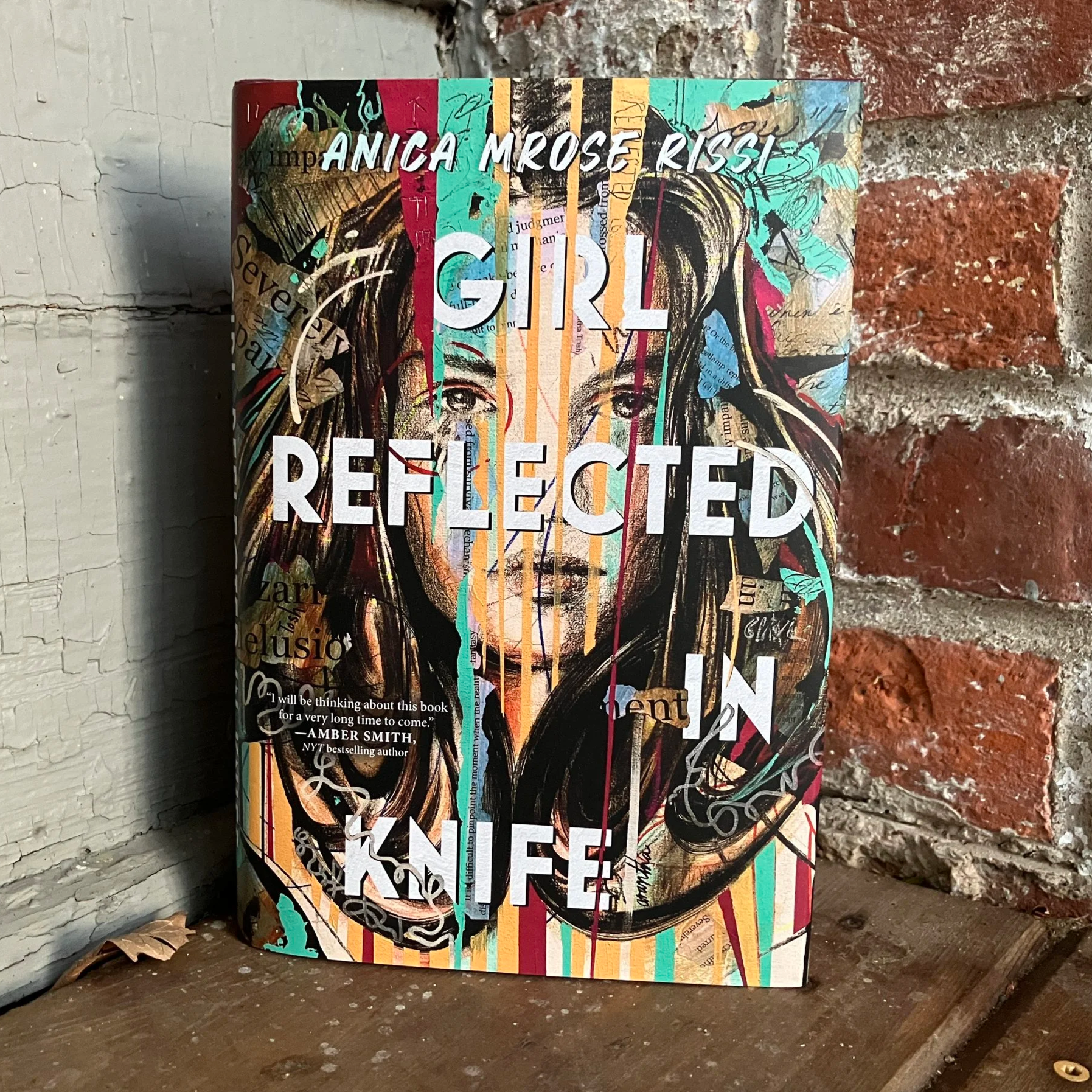 hardcover of Girl Reflected in Knife in a corner between a brick wall and a gray painted wall