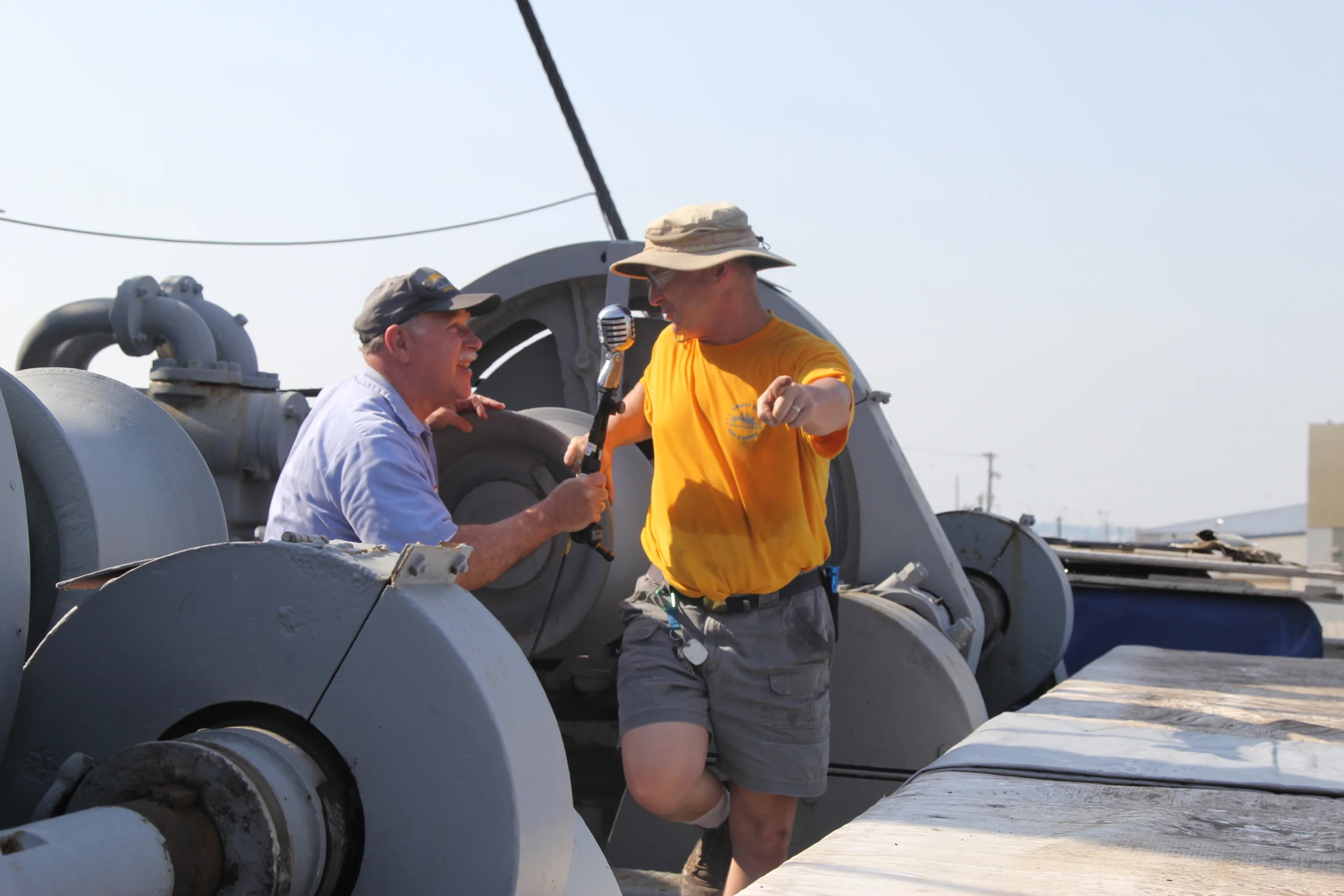 Howard directs Ray in microphone placement for the guest speakers before a cruise.