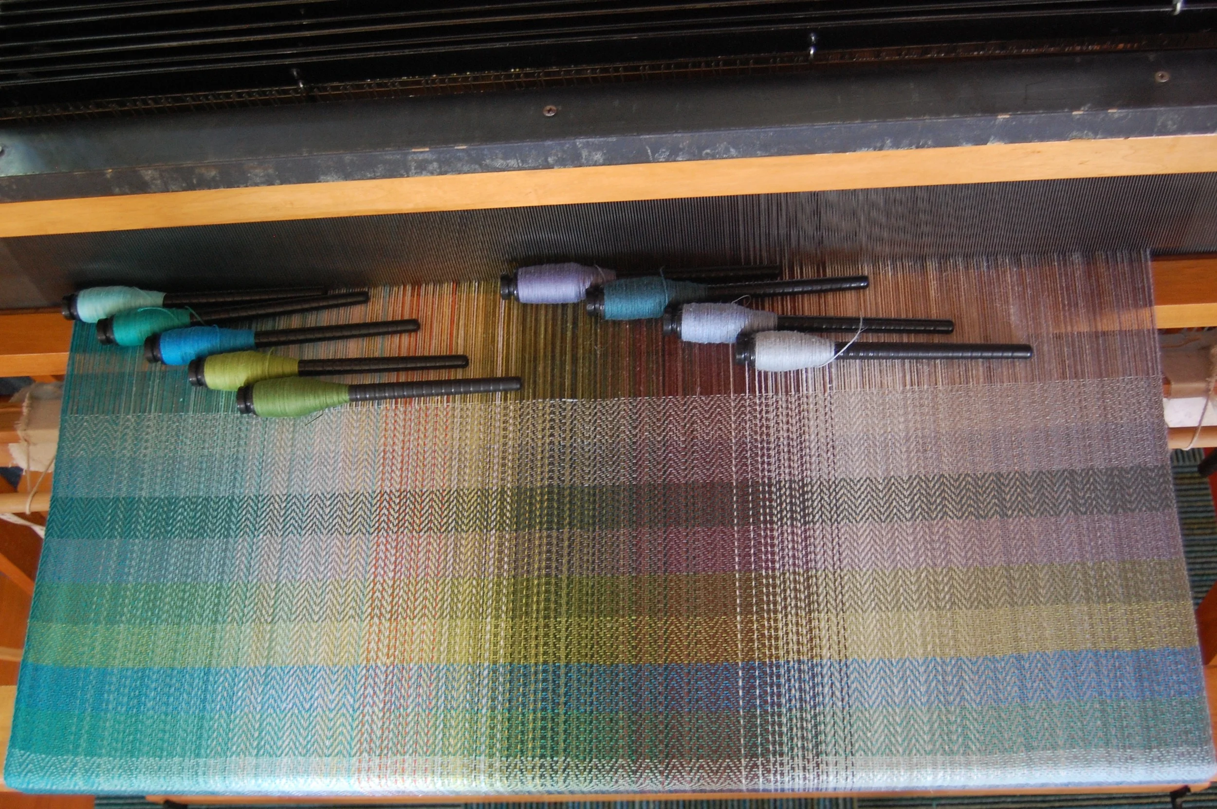 Cotton/Cottolin wefts (from bottom of woven sample and left of pirns): Sea Foam EC, Blue-green EC, Turquoise, light green, dark green, Blue-grey EC, Peacock organic cotton, Neptune cottolin and Green-grey cottolin.