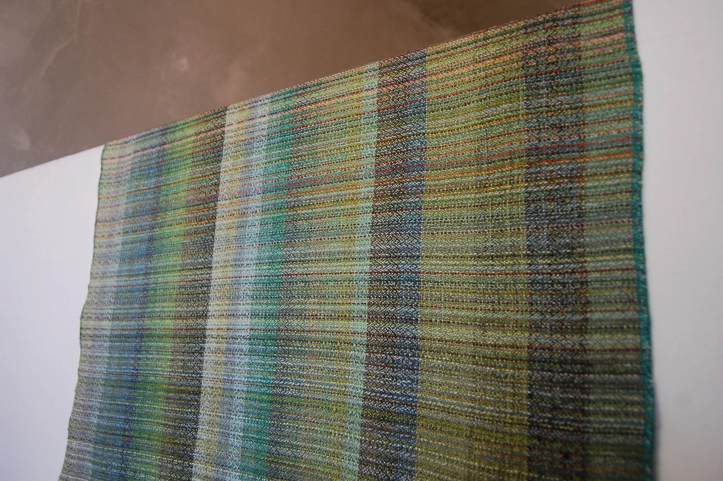 The weft sample piece - wet finished. Cottolin colors are shown on the left from light green to dark green; cotton colors are shown in the middle from light green to dark green; special fibers are the 4 wider stripes on the right.
