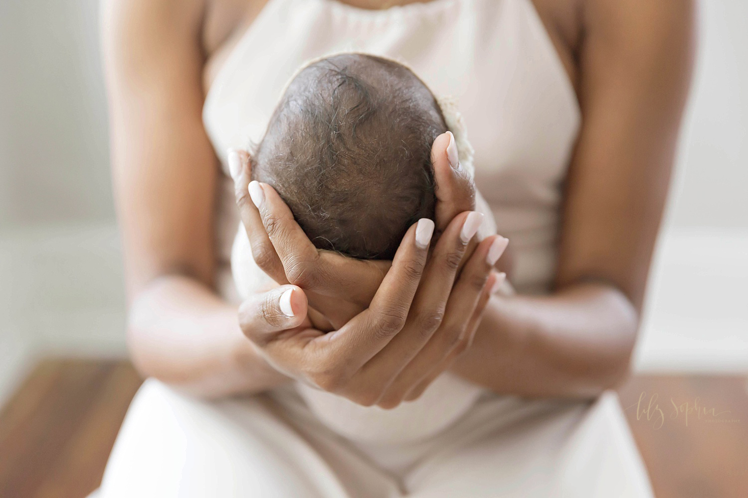  Close up image of a African American newborn's head,&nbsp;cradled in her mother's hands.&nbsp; 