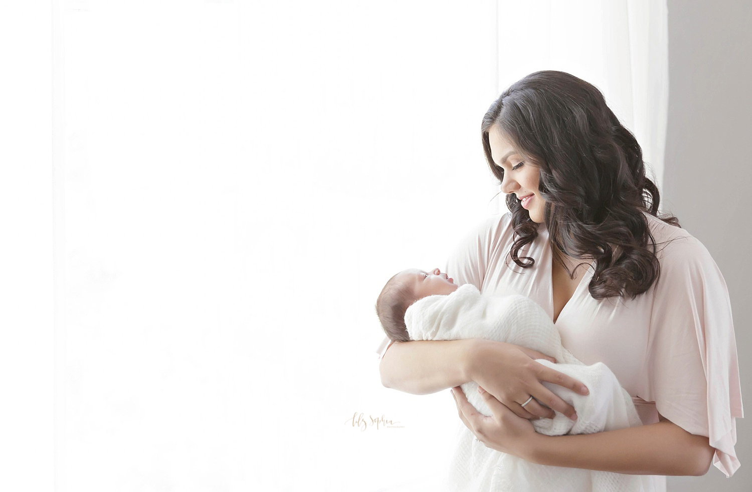  Image of a mother holding her newborn, baby, daughter in her arms,&nbsp;looking down and smiling at her.&nbsp; 