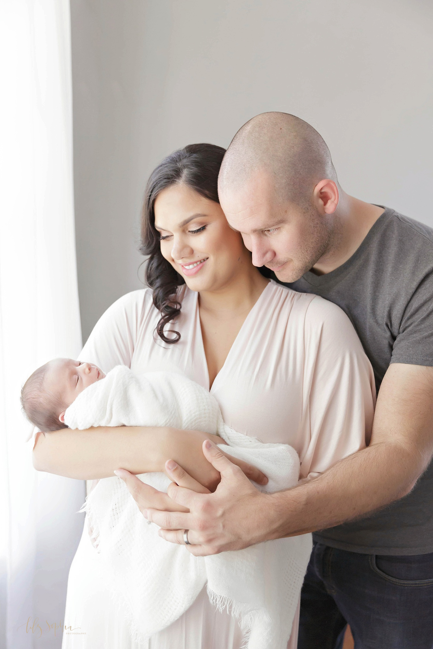  Image of a mother and father holding their infant, newborn, baby, daughter. 