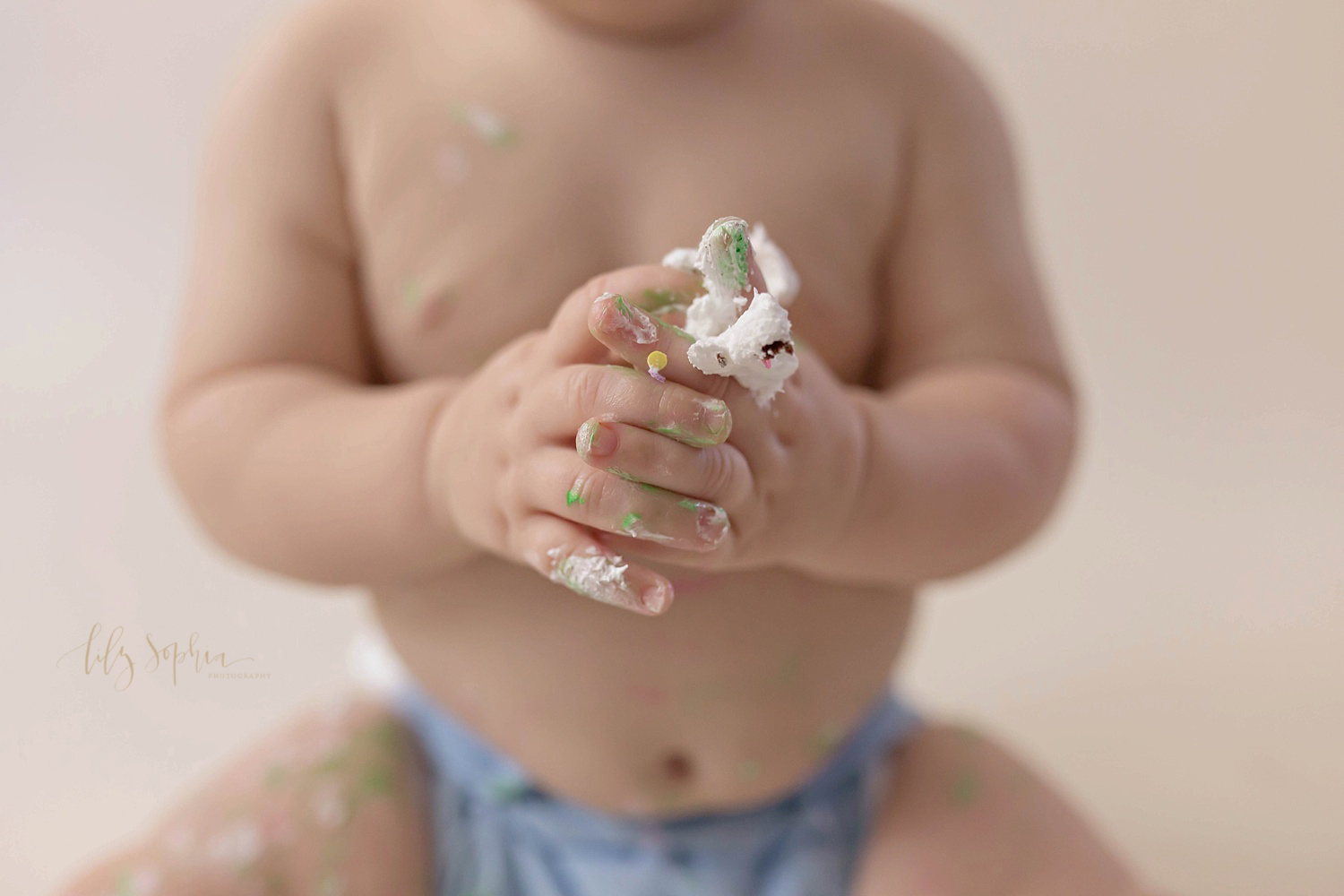  Close up of the icing covered fingers of a one year old, baby, boy.&nbsp; 