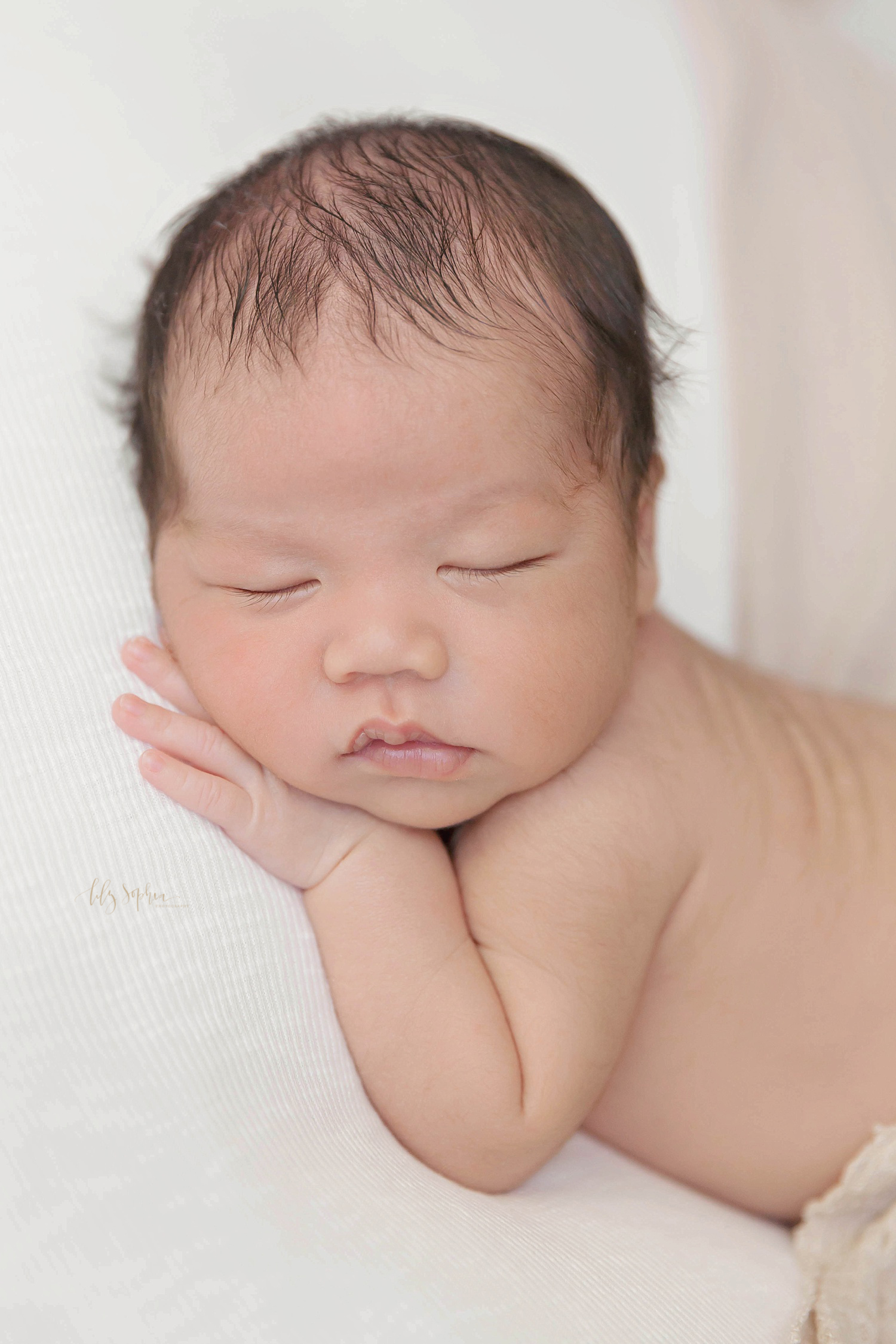  Image of sleeping Asian newborn boy with his hand under his face.&nbsp; 