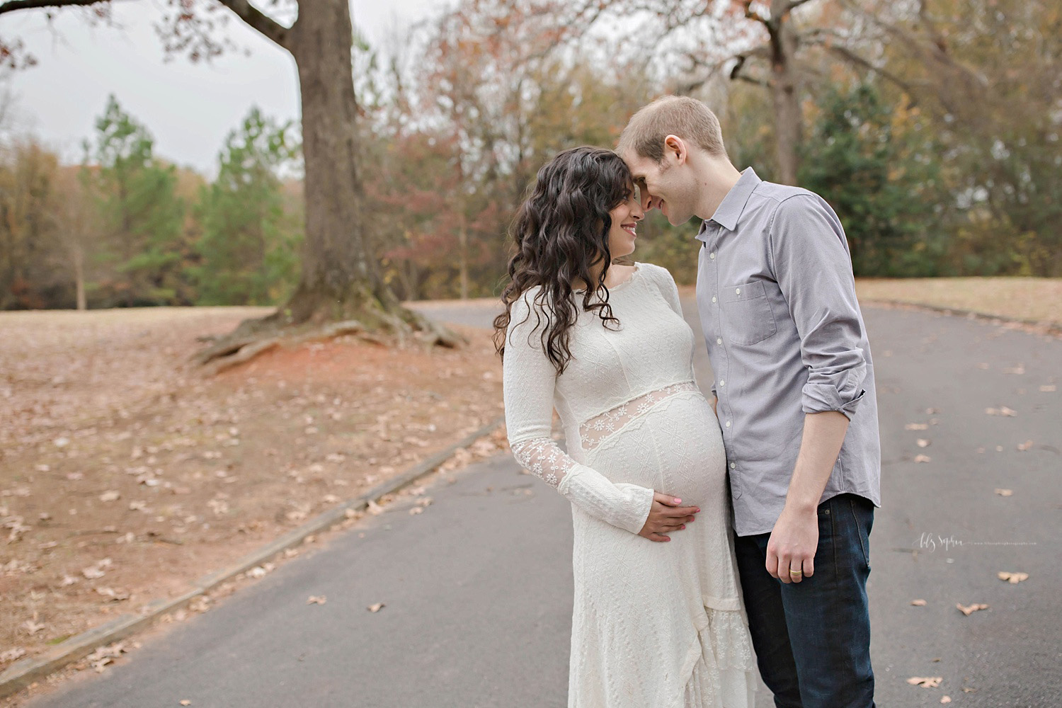 Pregnant woman in white dress nuzzling husband in local Atlanta park