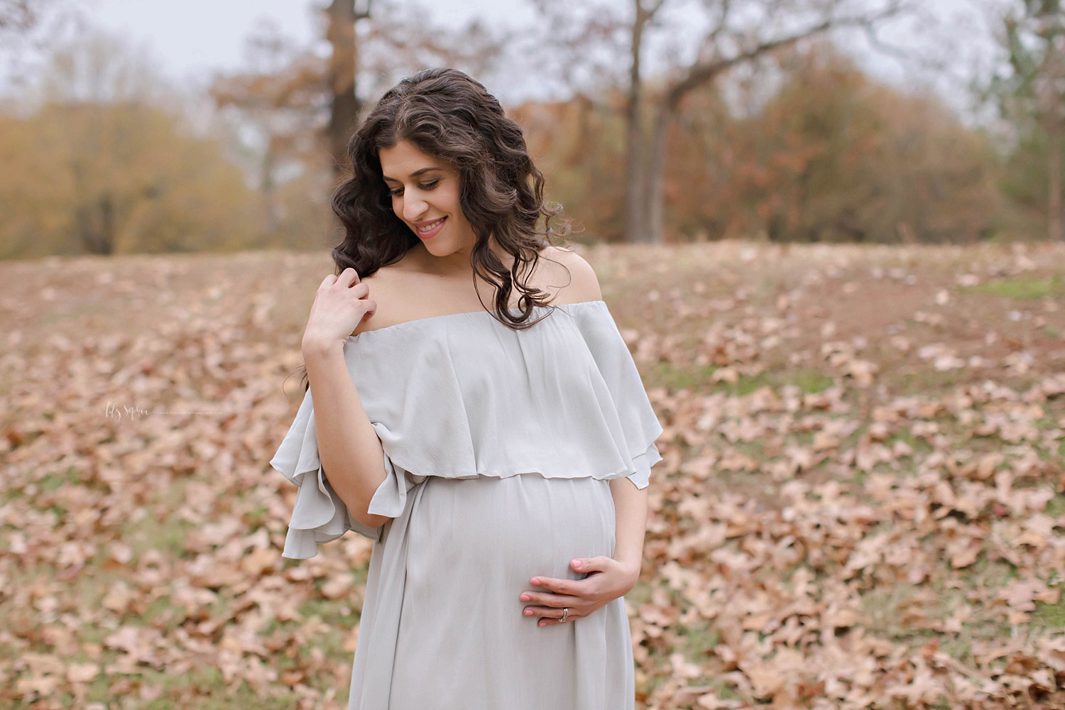 Beautiful pregnant woman wearing off the shoulder dress in local Atlanta park