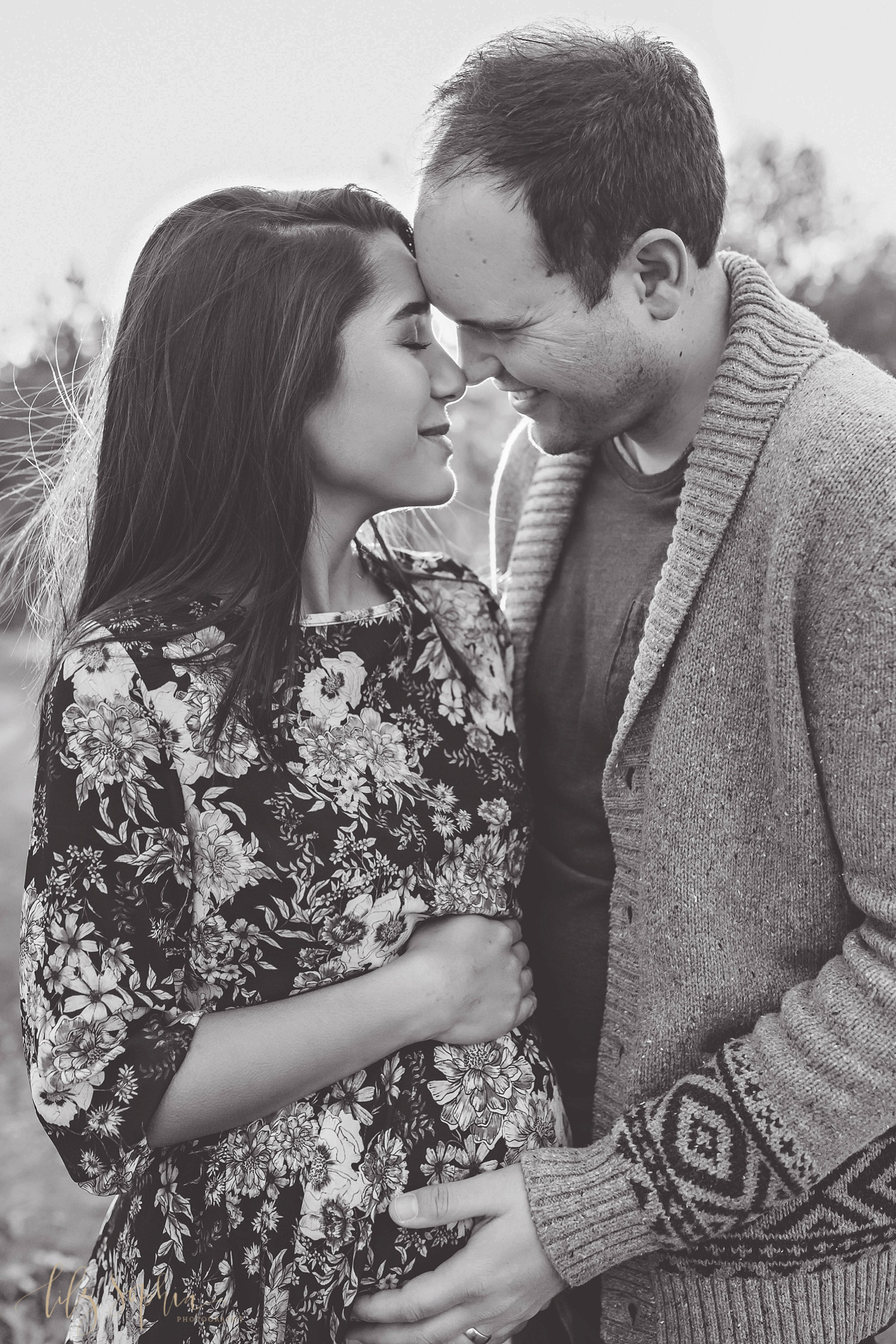  Black and white image of a pregnant woman and her husband touching foreheads.&nbsp; 