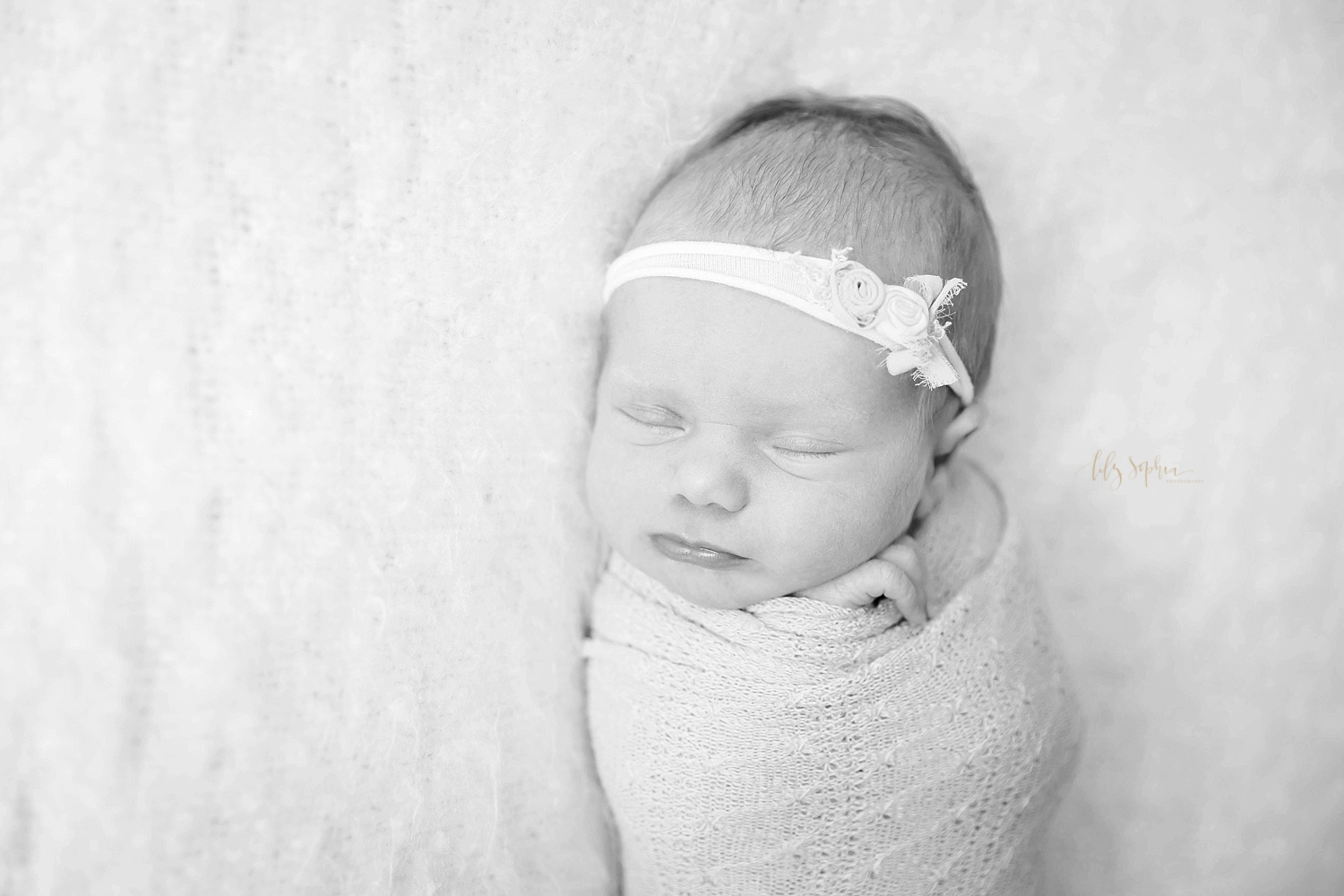 Sleeping newborn baby girl swaddled with headband in Atlanta GA