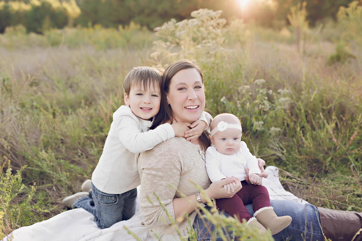  An Atlanta mom with her little boy and baby girl during a family portrait session in a field in Atlanta.&nbsp; 