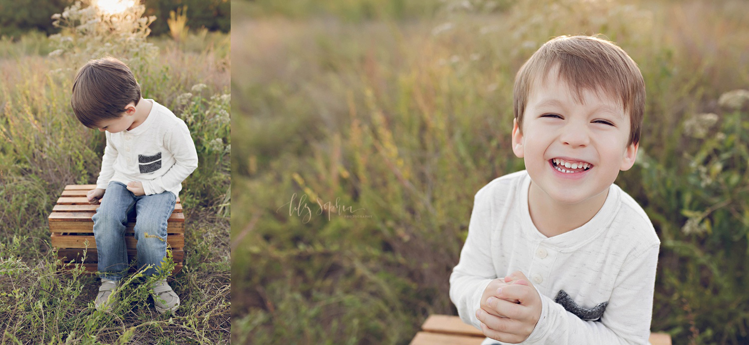  A little boy sitting on a wooden crate in an Atlanta field smiling and laughing during his family portrait session by Lily Sophia Photography 
