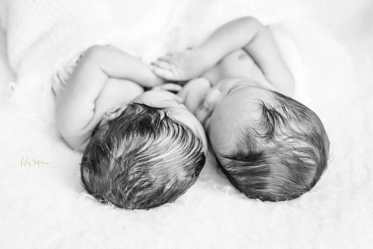  Black and white image of sleeping, African American, newborn boy/girl twins cuddled up together taken from a top angle. 