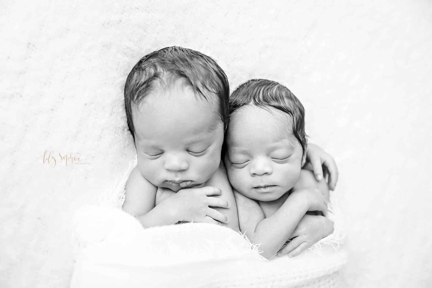  Black and white image of sleeping, African American, newborn boy/girl twins, with the boy having his arm around his sister and his hand on his chest taken at the natual light studio of Lily Sophia Photography. 