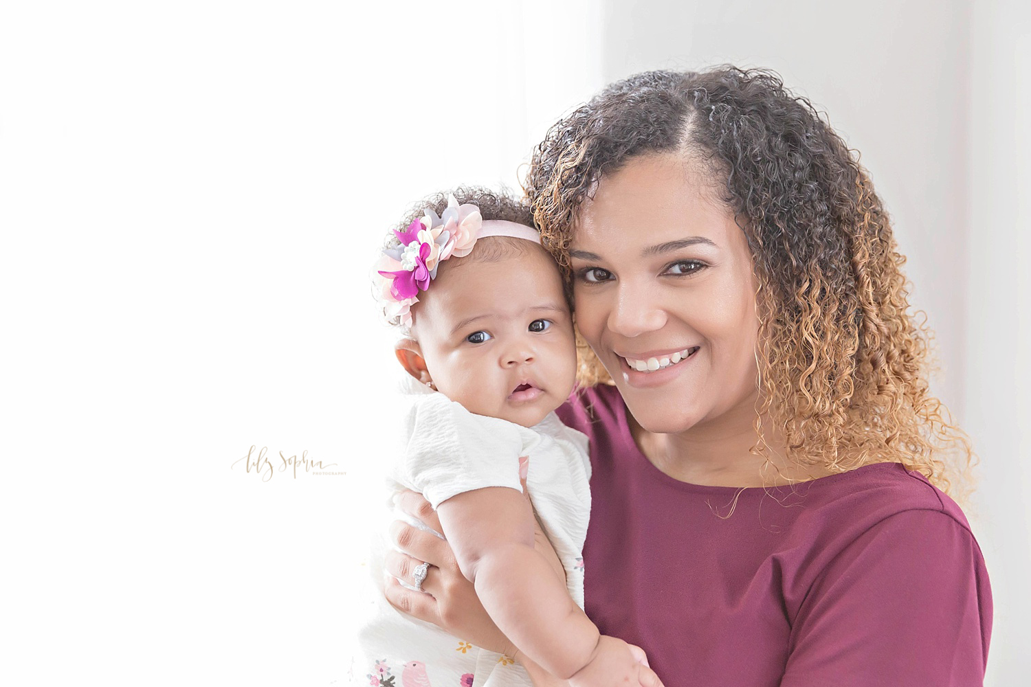  Image of an African American mother holding up her three month old daughter and smiling.&nbsp; 