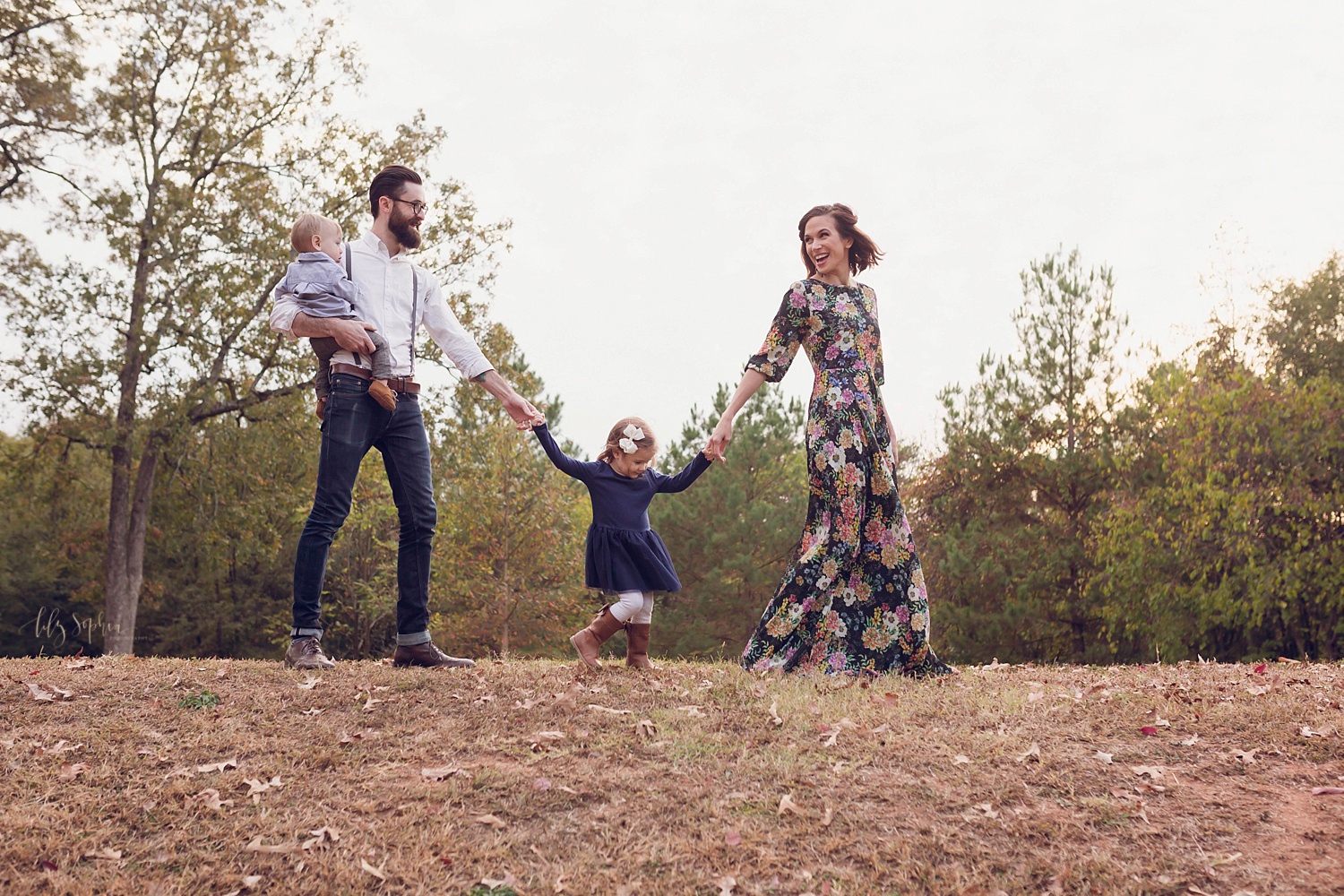  A portrait of a family of four walking and holding hands on a hilltop in Atlanta.&nbsp; 