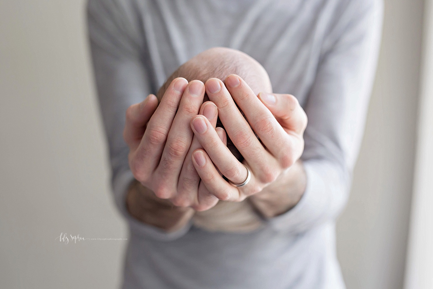  Image of a fathers hands holding his sleeping, newborn, son's head.&nbsp; 