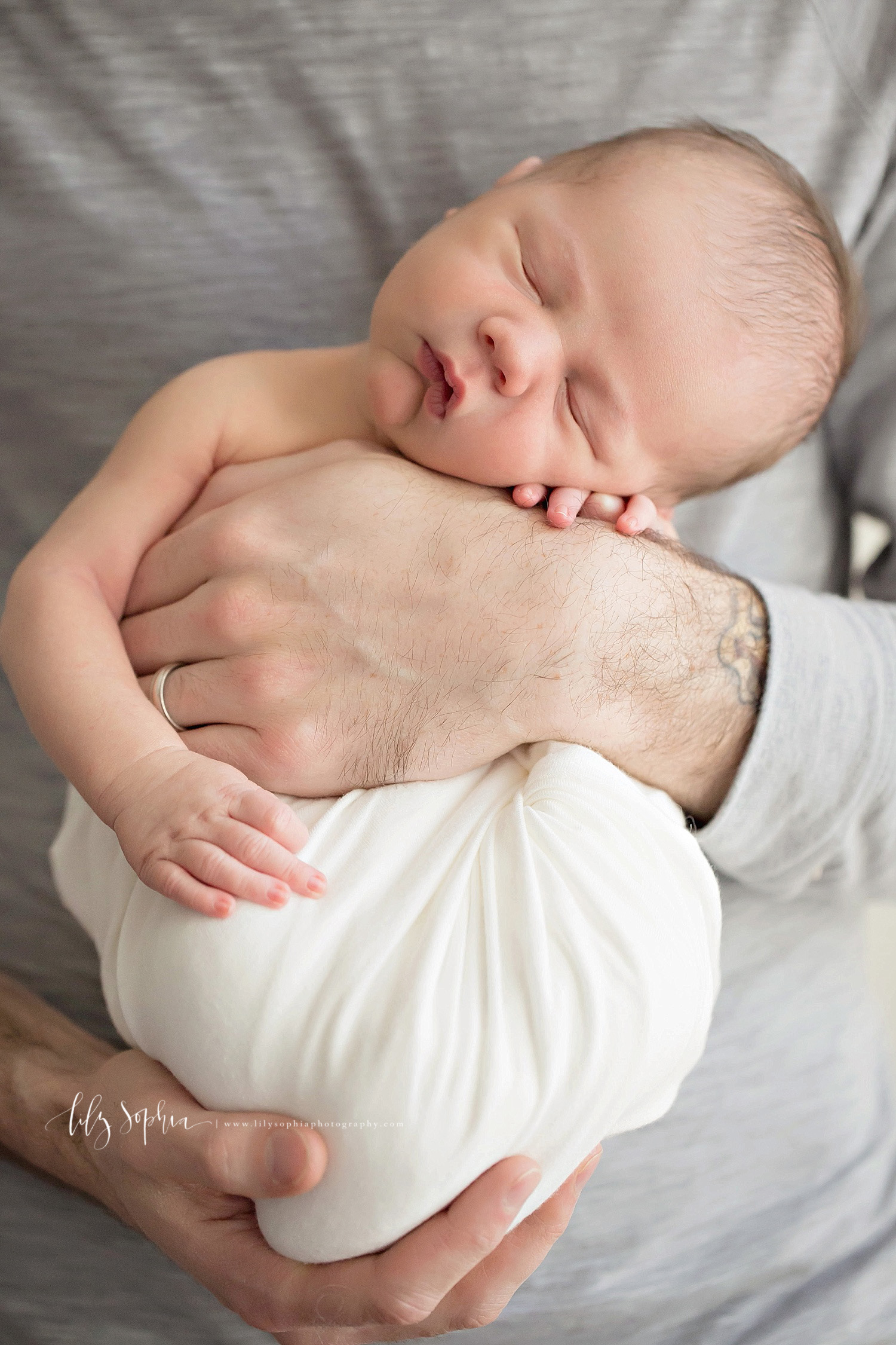  Close up image of a father's hand around his sleeping's son chest, while his son rests his head on his arm.&nbsp; 