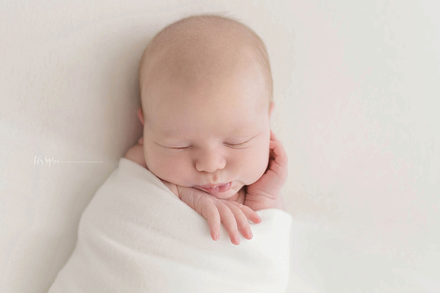  Image of a sleeping, newborn, boy, wrapped in a blanket with his hands peeking out. 