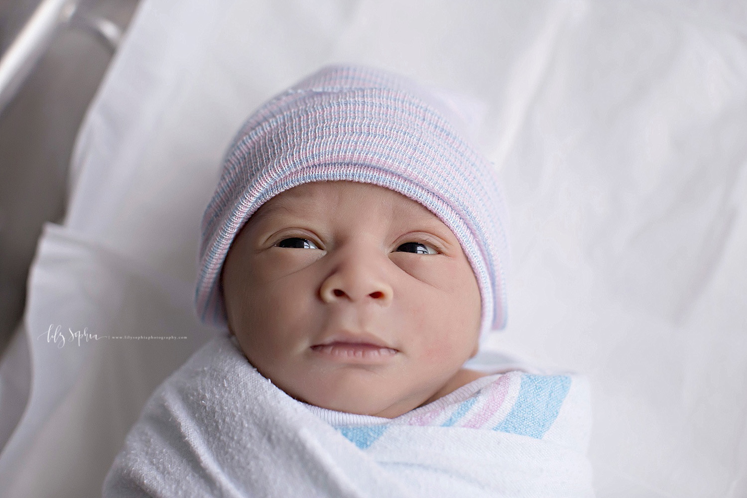  Image of an African American, infant, newborn, baby, boy with his eyes open, laying in his hospital bassinet.&nbsp; 