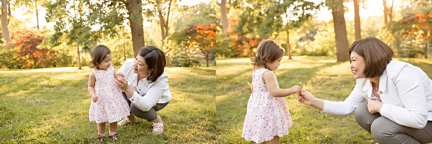  Image of an Asian woman, crouching down, next to her daughter and admiring the clover flower that she picked.&nbsp; 