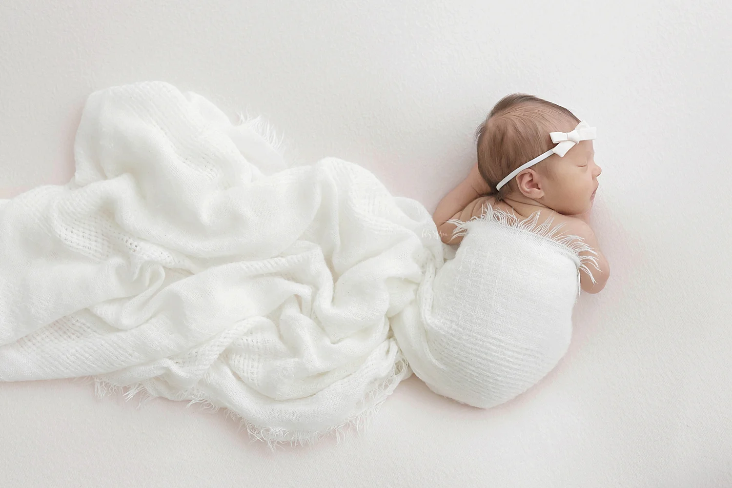 Image of a sleeping, newborn, baby, girl, on her belly, with her hands tucked under her. 