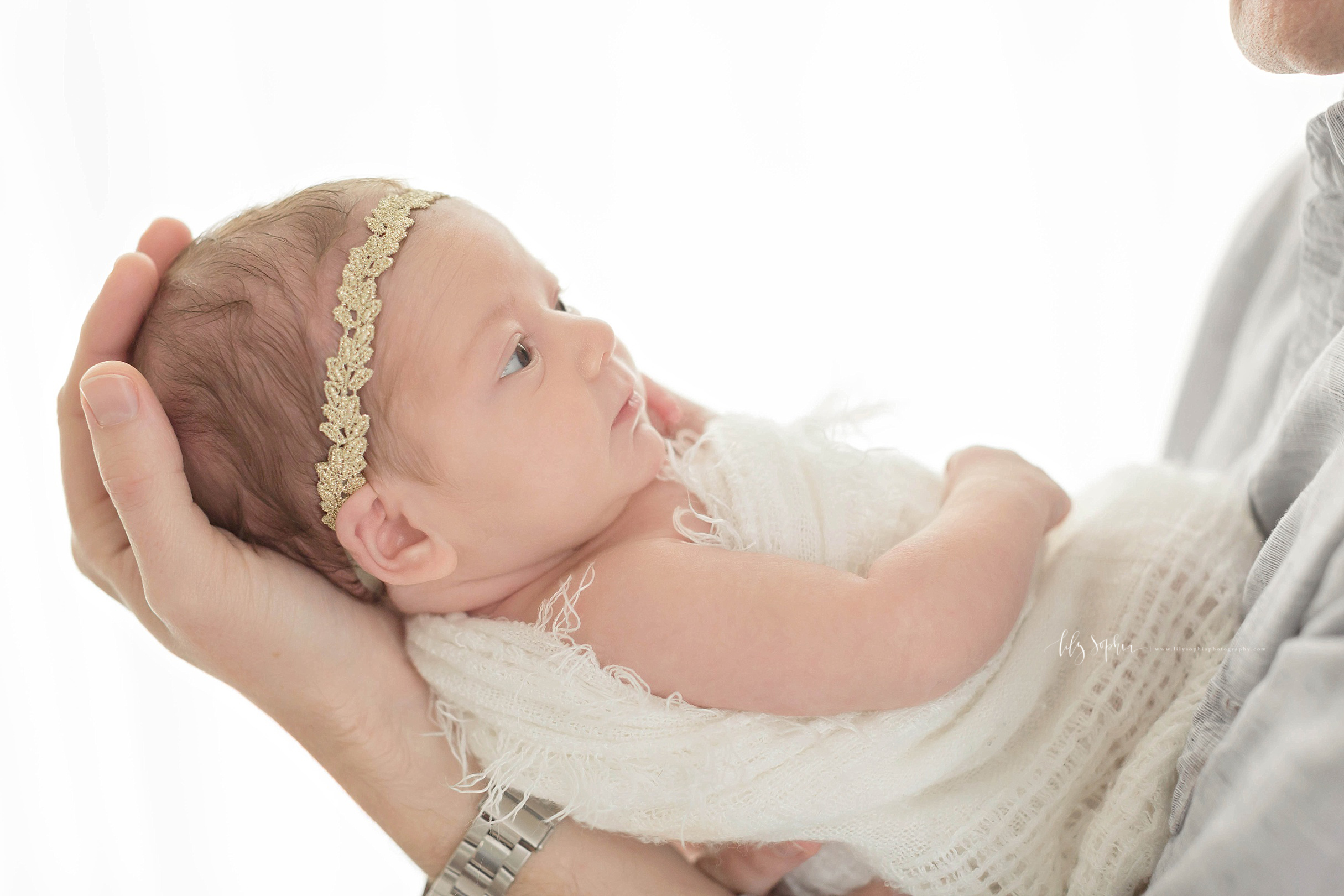  Image of a father, holding his newborn daughter, up in his hand while she looks up at him.&nbsp; 