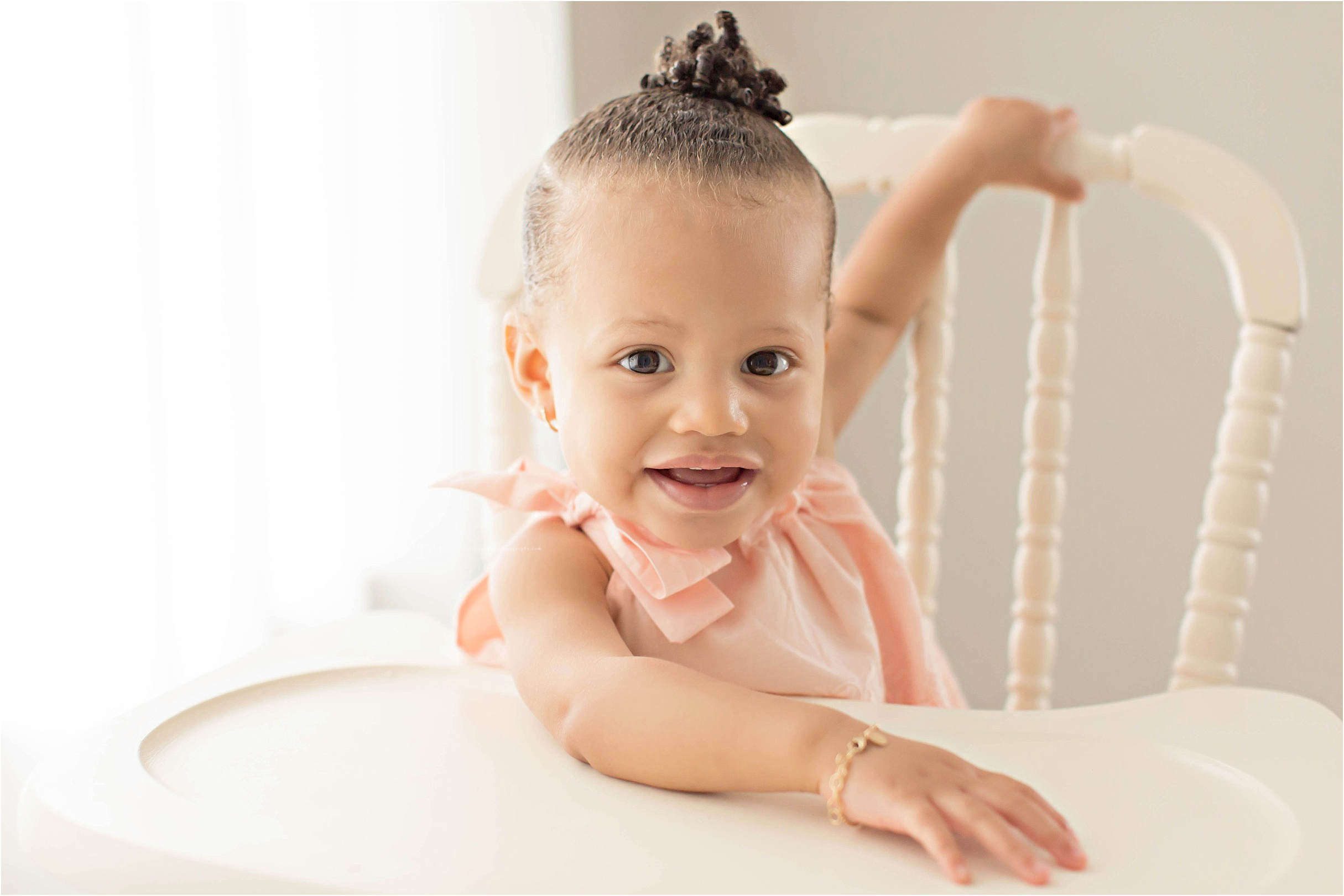  Image of an African American, baby, one year old, girl, sitting in a high chair and smiling.&nbsp; 