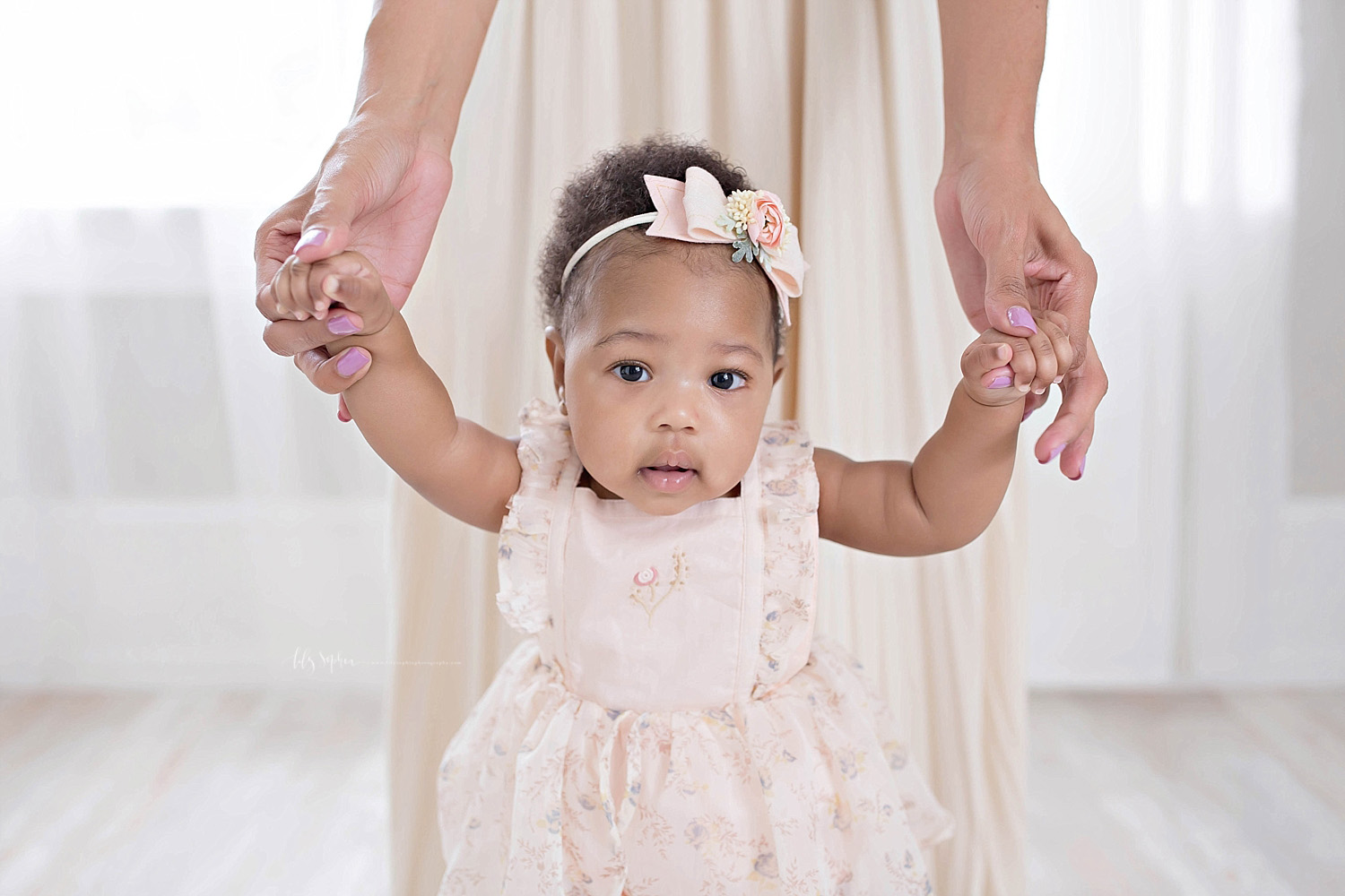  Image of a African American, baby, girl, standing up with the help of her mother.&nbsp; 