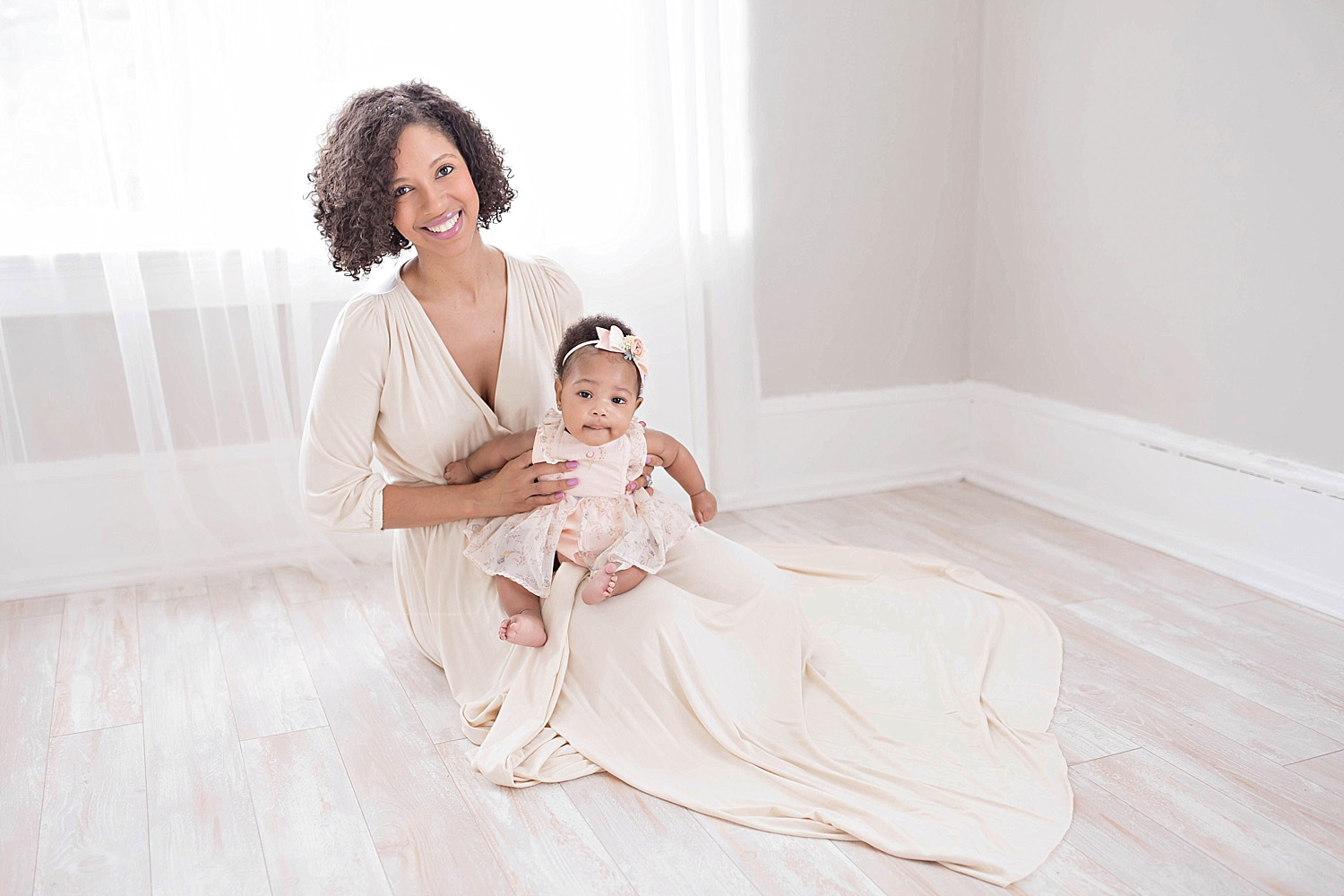  Image of an African American mother, sitting on the floor, smiling, and holding her 6 month old baby on her lap.&nbsp; 