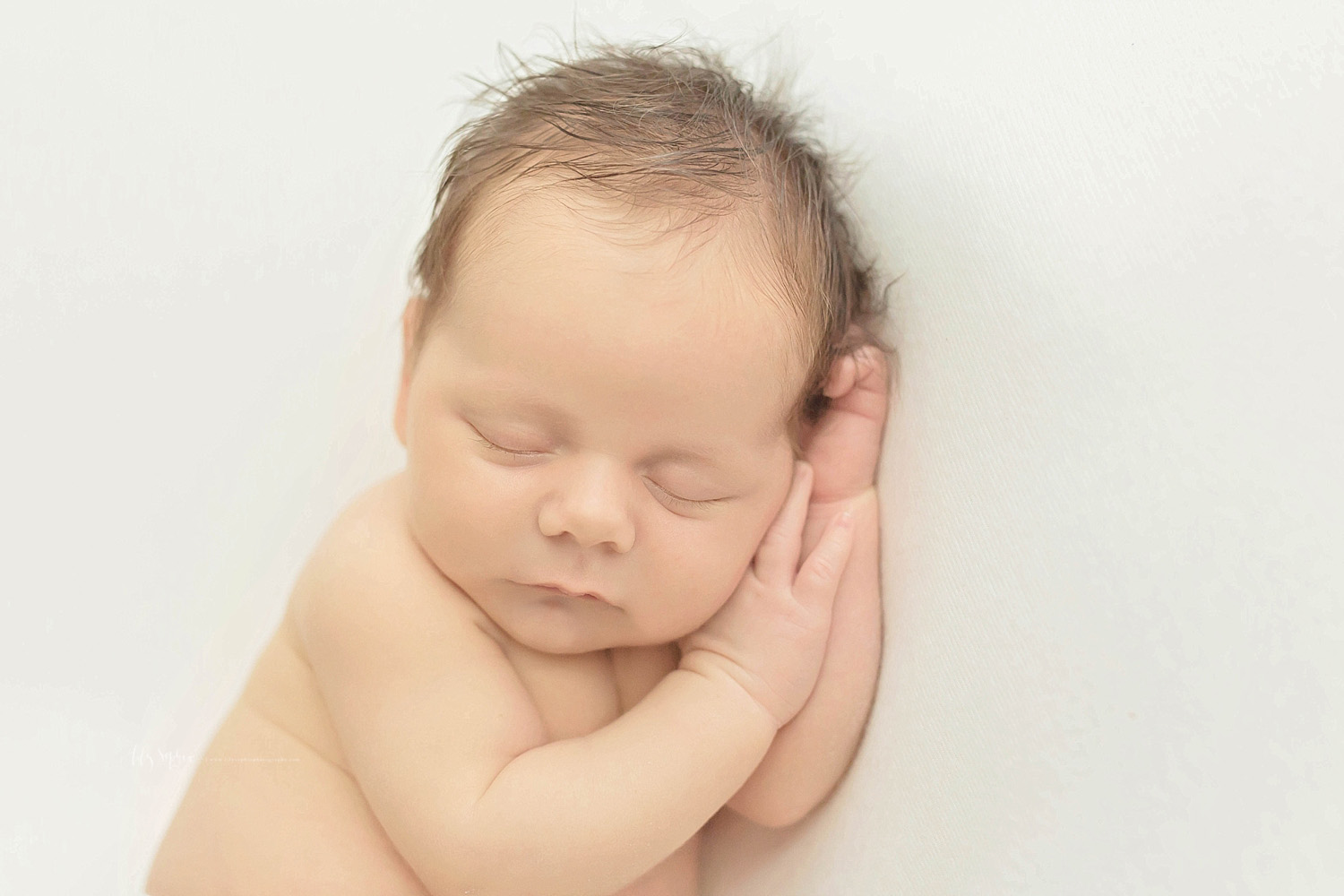 Image of a newborn, baby, boy with his hands under his head, sleeping on his side.&nbsp; 