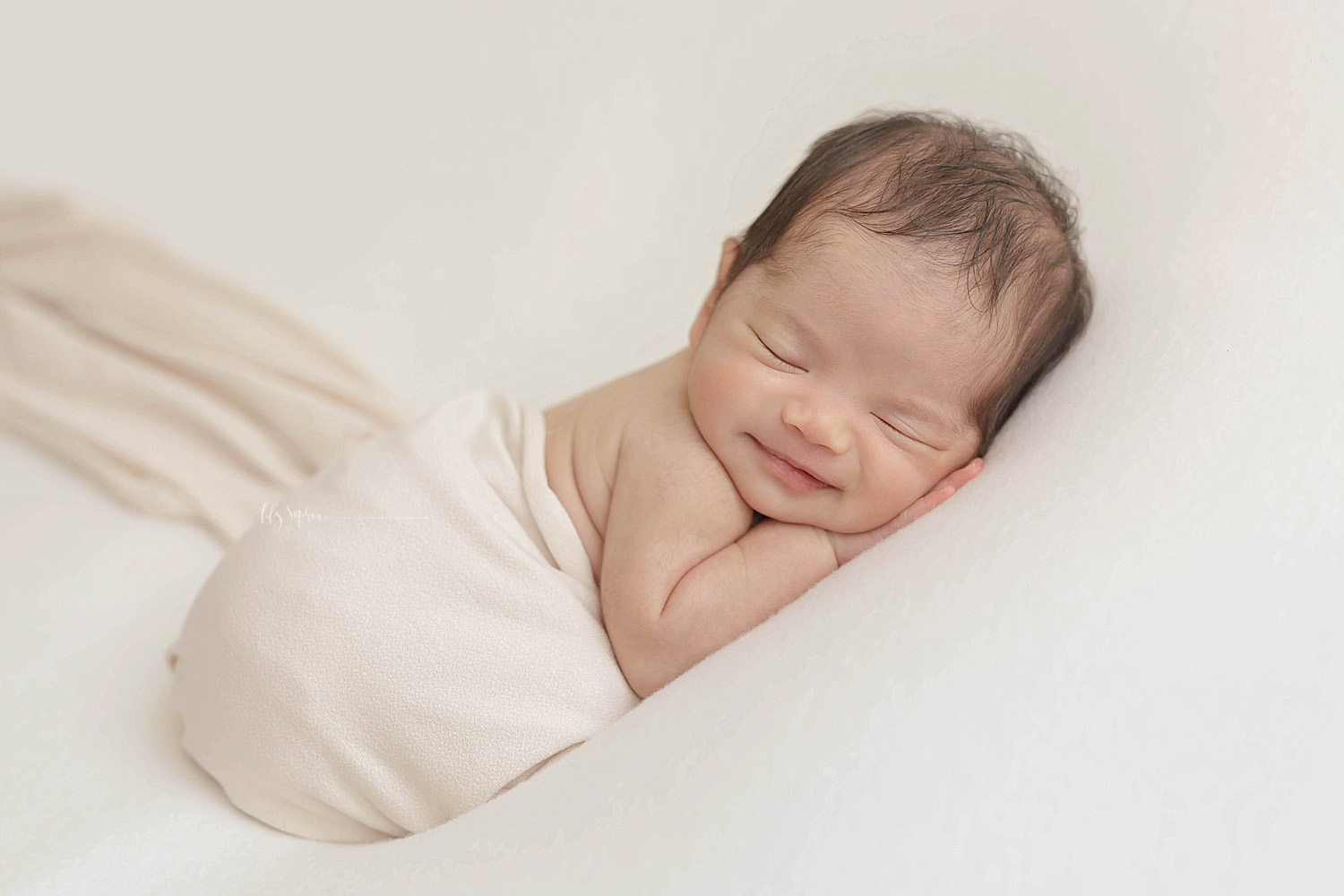  Image of a sleeping, baby, newborn, girl, on her stomach, with a grin on her face.&nbsp; 