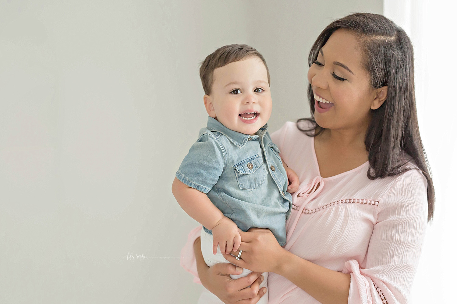  Image of a toddler boy, with dimples, smiling while in his mother's arms.&nbsp; 