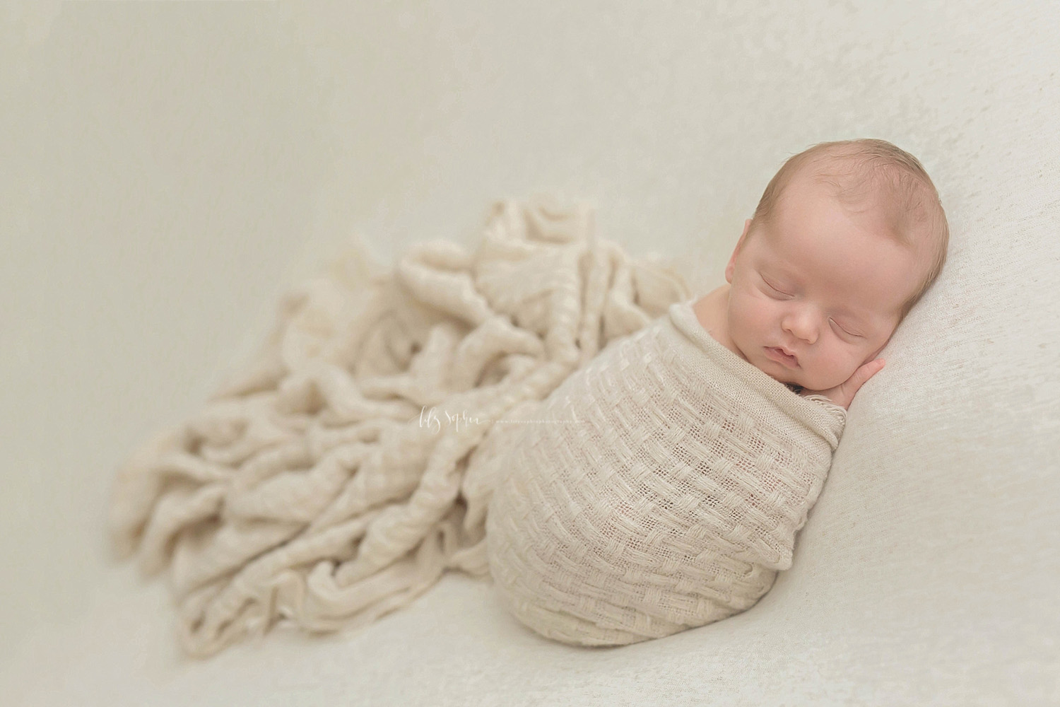 Image of newborn, baby, boy, sleeping on his belly, wrapped up in a tan, waffle weave blanket.&nbsp; 