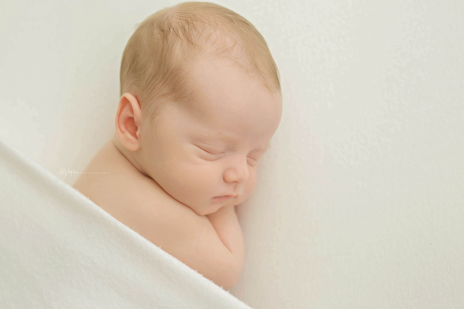  Image of baby boy, on his side, sleeping with his hands tucked up under his head.&nbsp; 