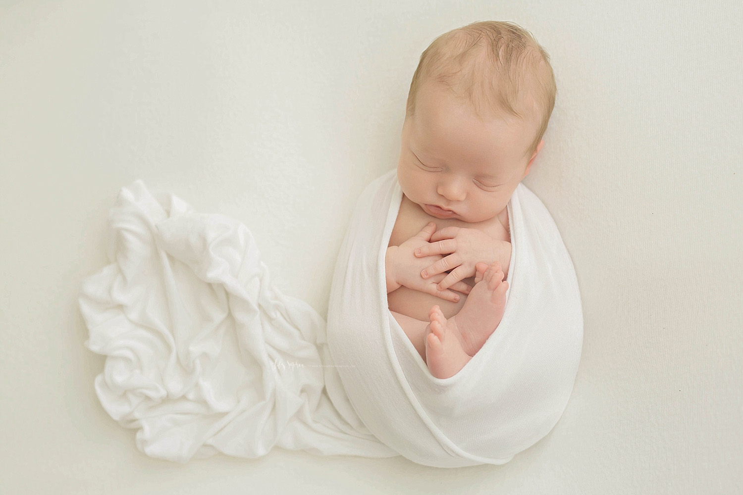  Image of a sleeping, baby, boy, wrapped up with his hands on his chest and his feet curled up on his belly.&nbsp; 