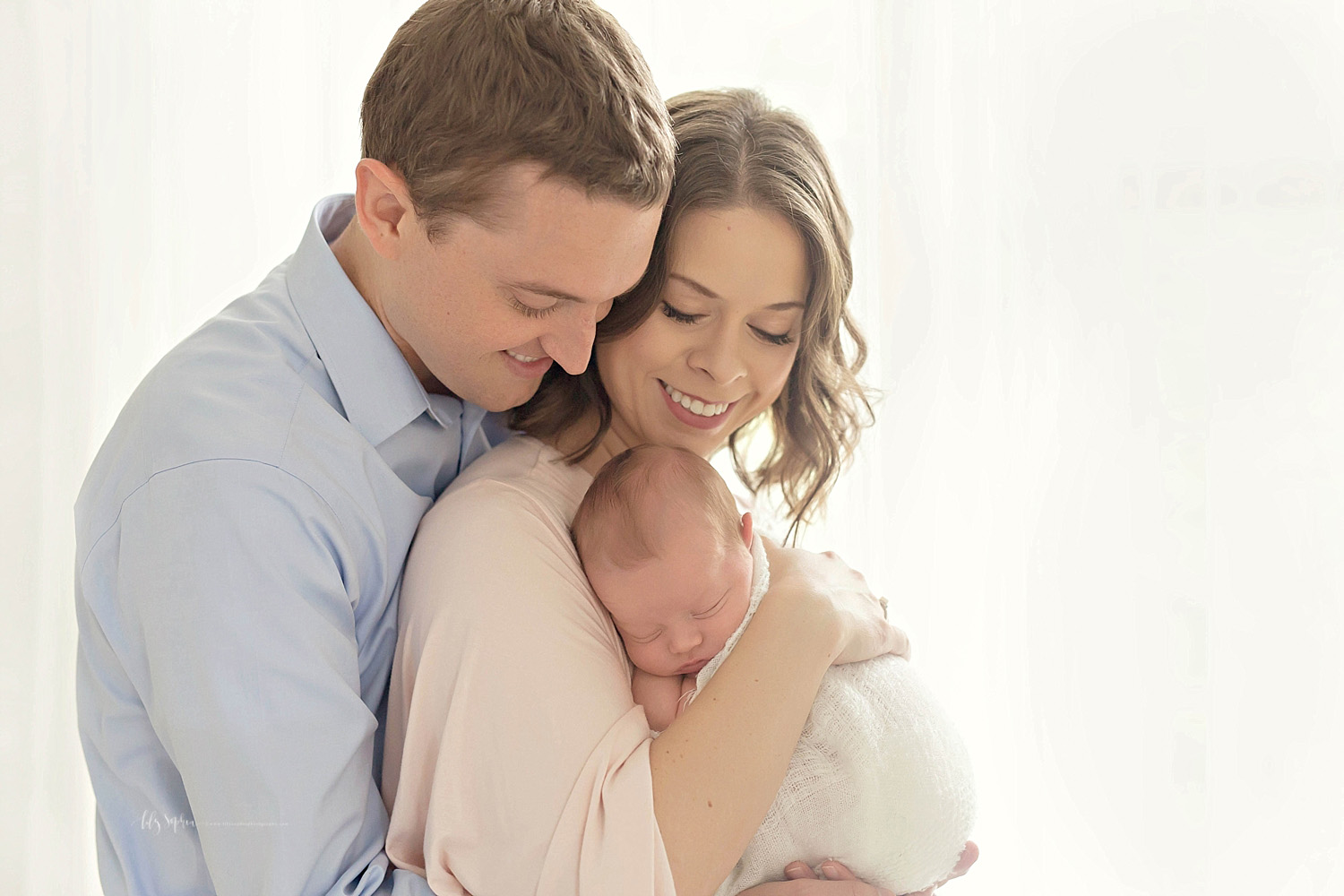  Image of new parents, smiling down at their sleeping newborn son while he sleeps in his mother's arms.&nbsp; 