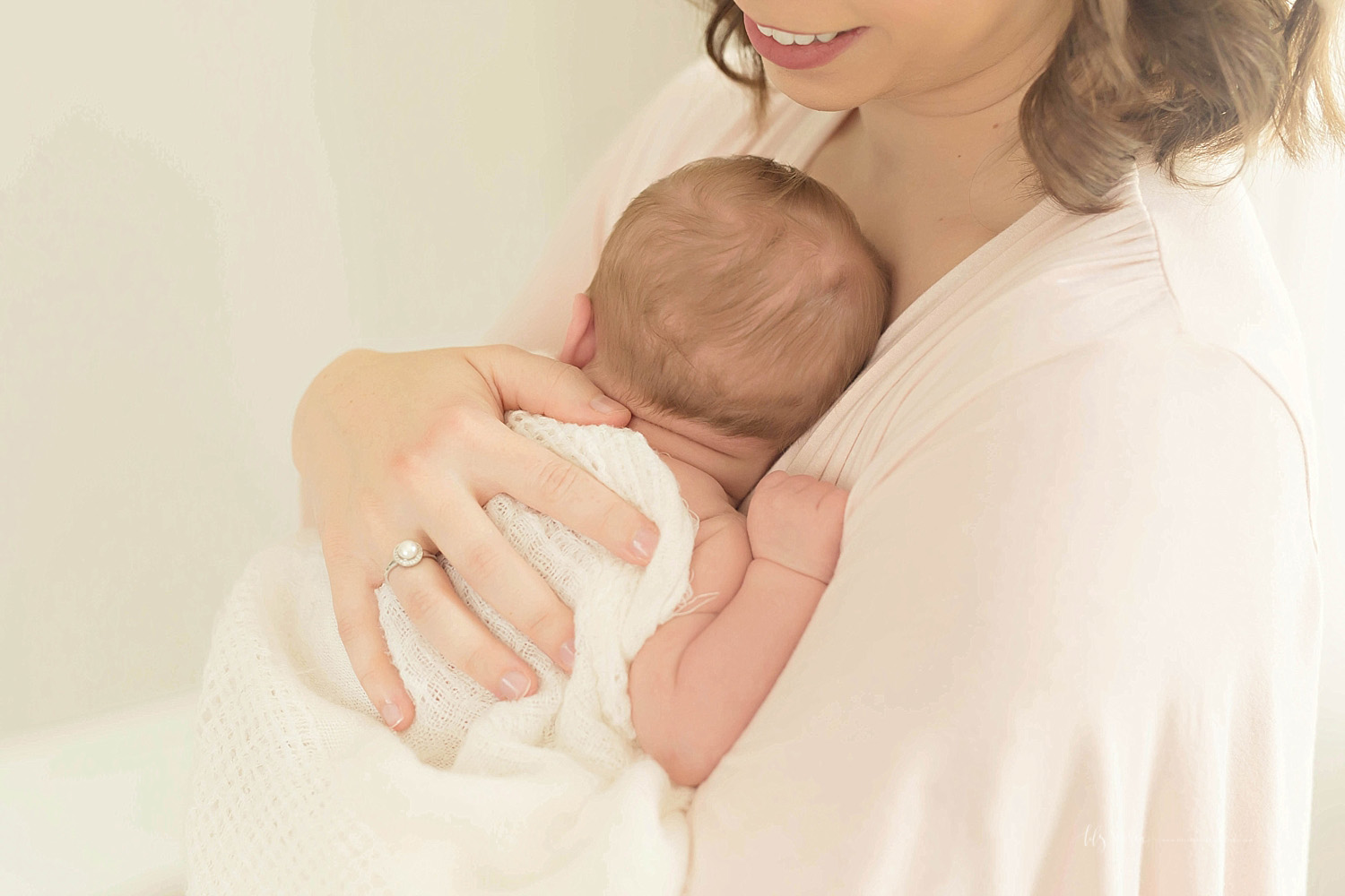  Image of a sleeping, newborn, baby boy, with his mother's hand on his back, while she smiles down at at him&nbsp; 
