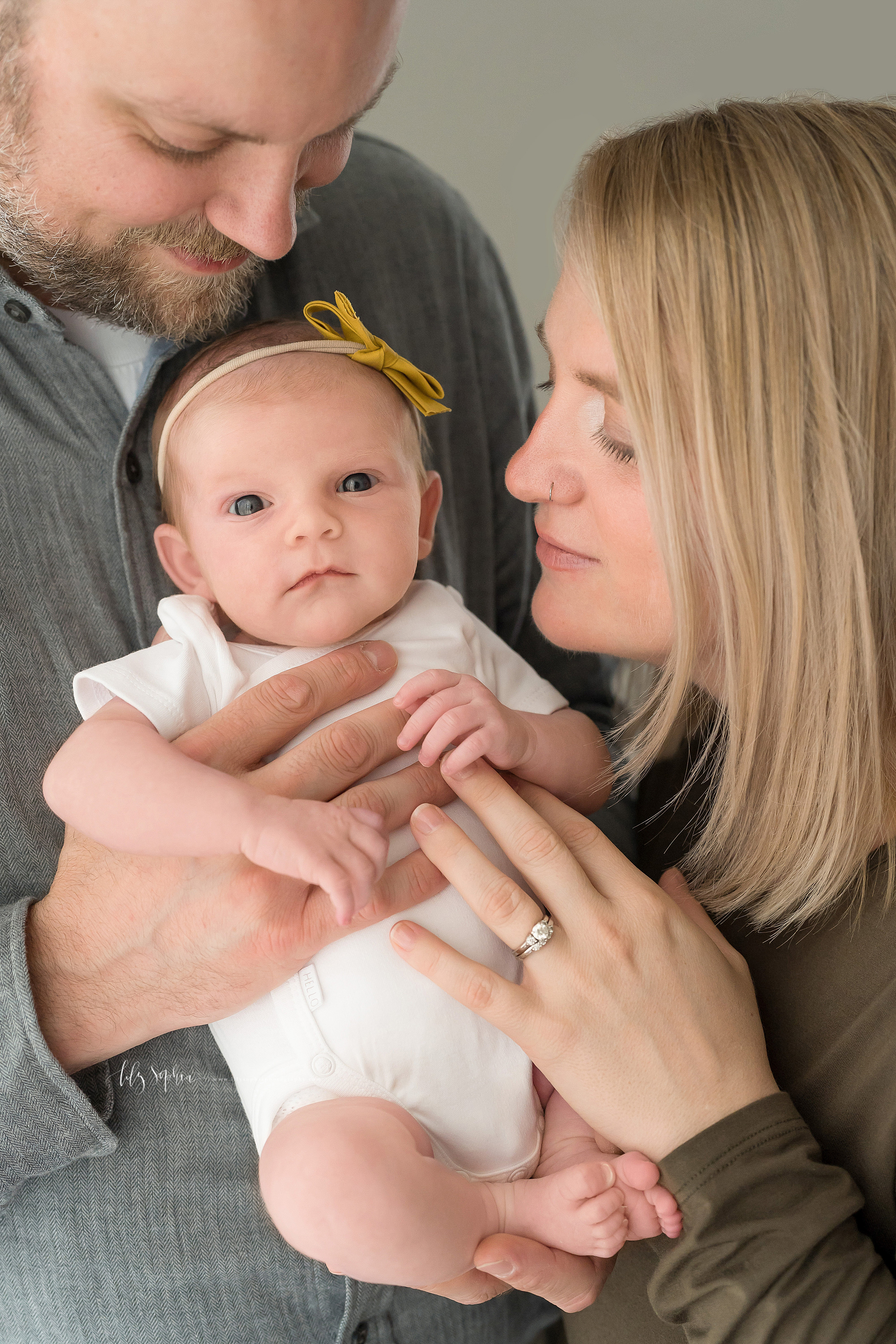  Family photo of a newborn girl and her parents taken in a natural light Atlanta studio. 