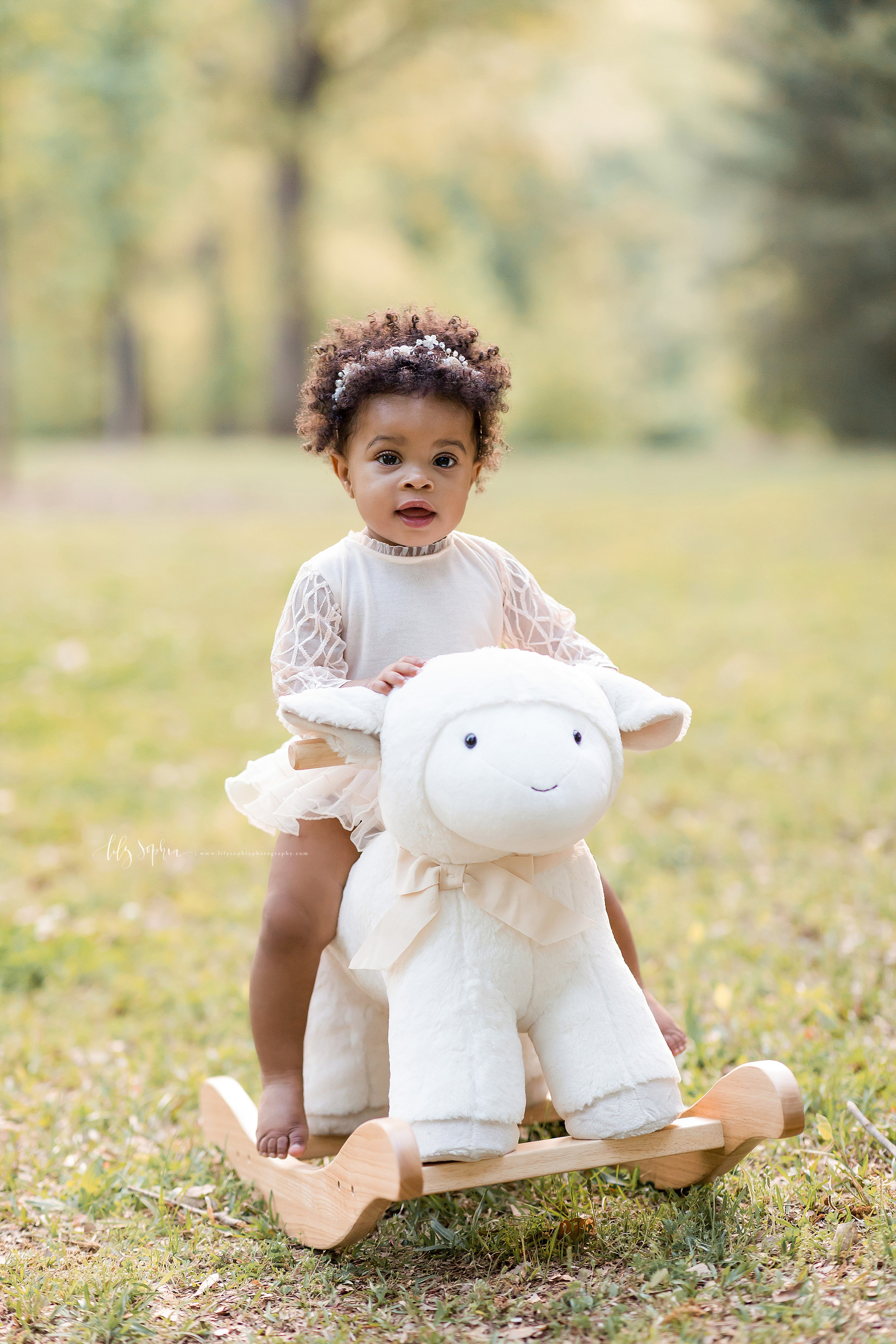 Image of an African-American one year old girl riding a rocking lamb at sunset in an Atlanta park.